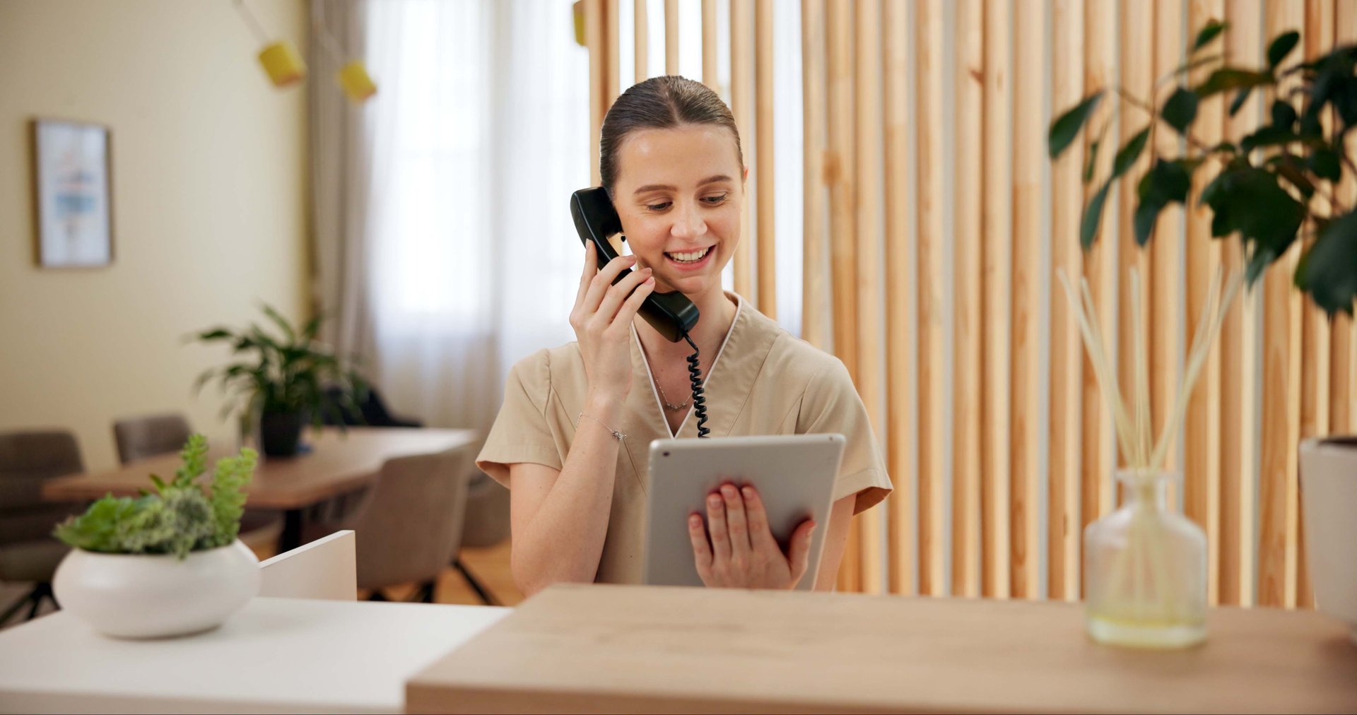 Phone call, spa and woman at reception with tablet checking website for online booking schedule. Consultant, receptionist or girl at front desk on telephone, digital app or appointment at hotel salon