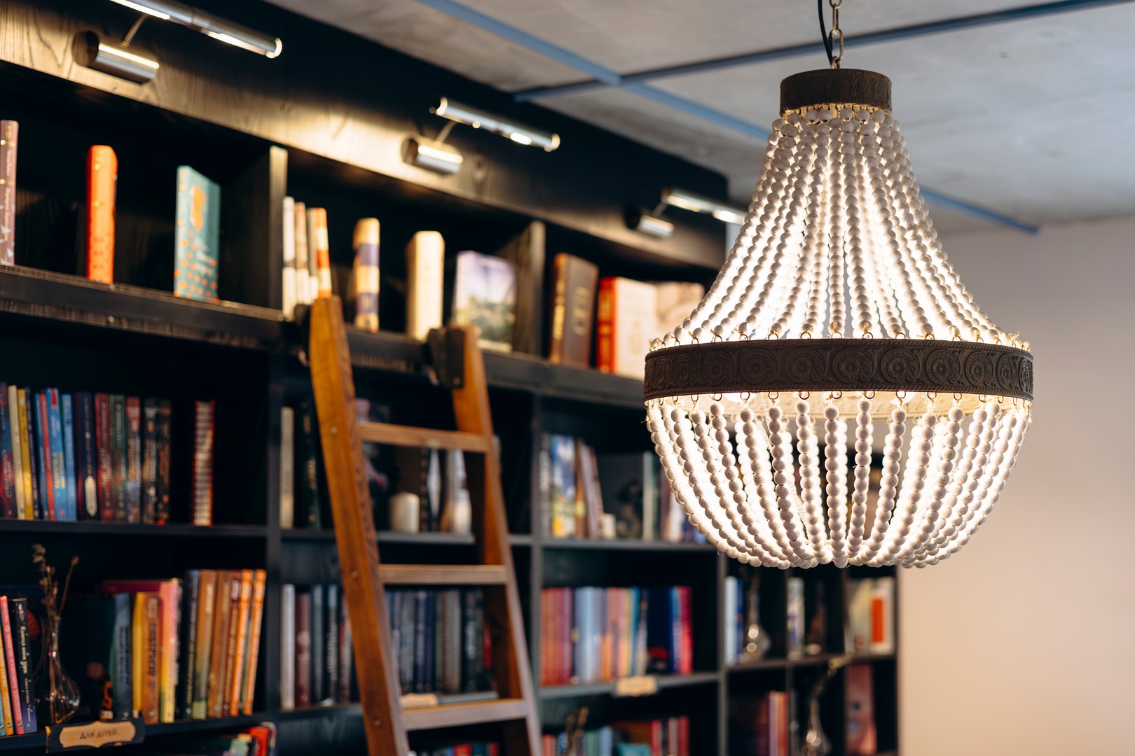 Vintage chandelier in an old bookstore with a wooden ladder in the background, cozy atmosphere. Copy space.