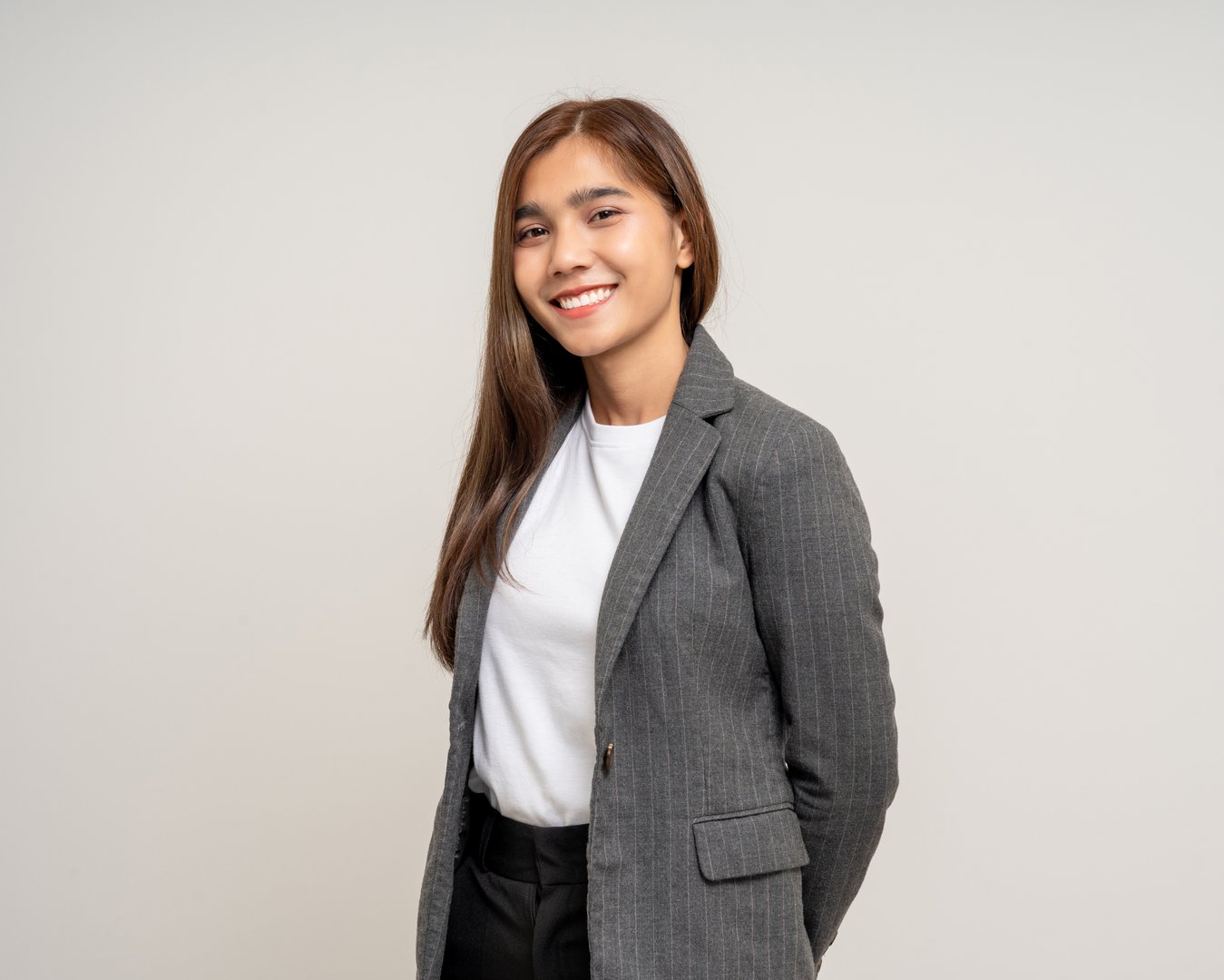 Attractive Young asian business woman smiling to camera standing pose on isolated white background. Latin Female around 25 in black suit portrait shot in studio.