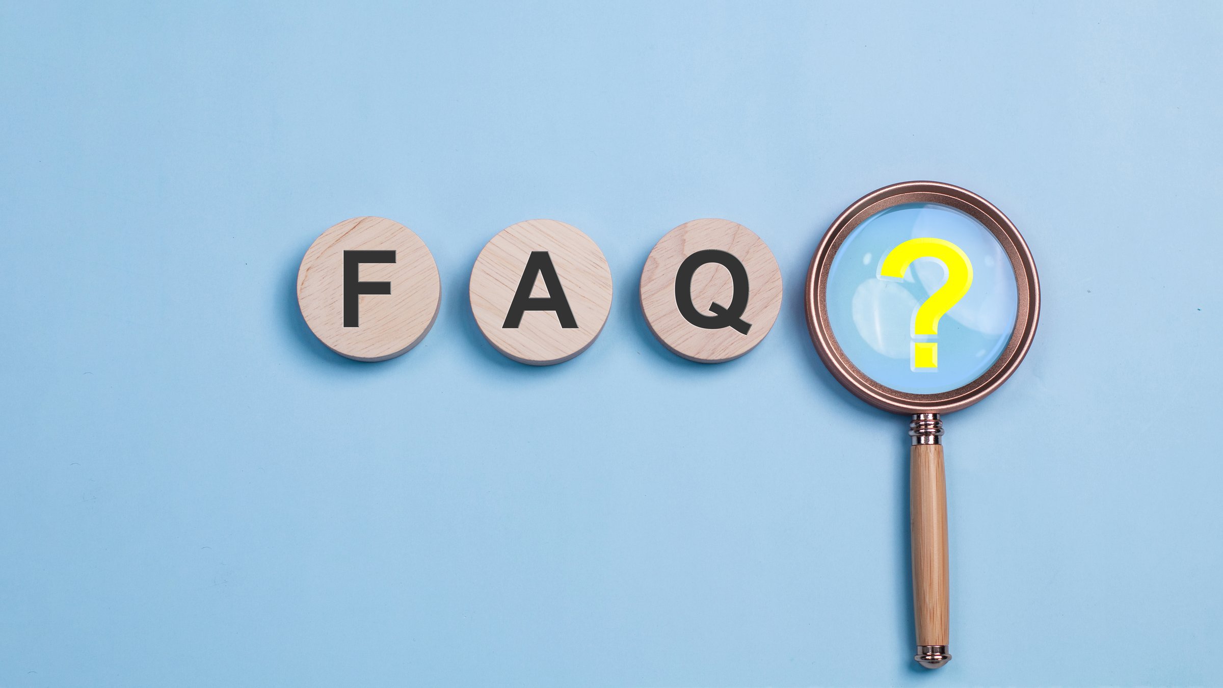 FAQ, frequently asked questions concept. Three wooden FAQ tiles and a magnifying glass with a yellow question mark. asked questions and answers. Instructions and rules on Internet sites.