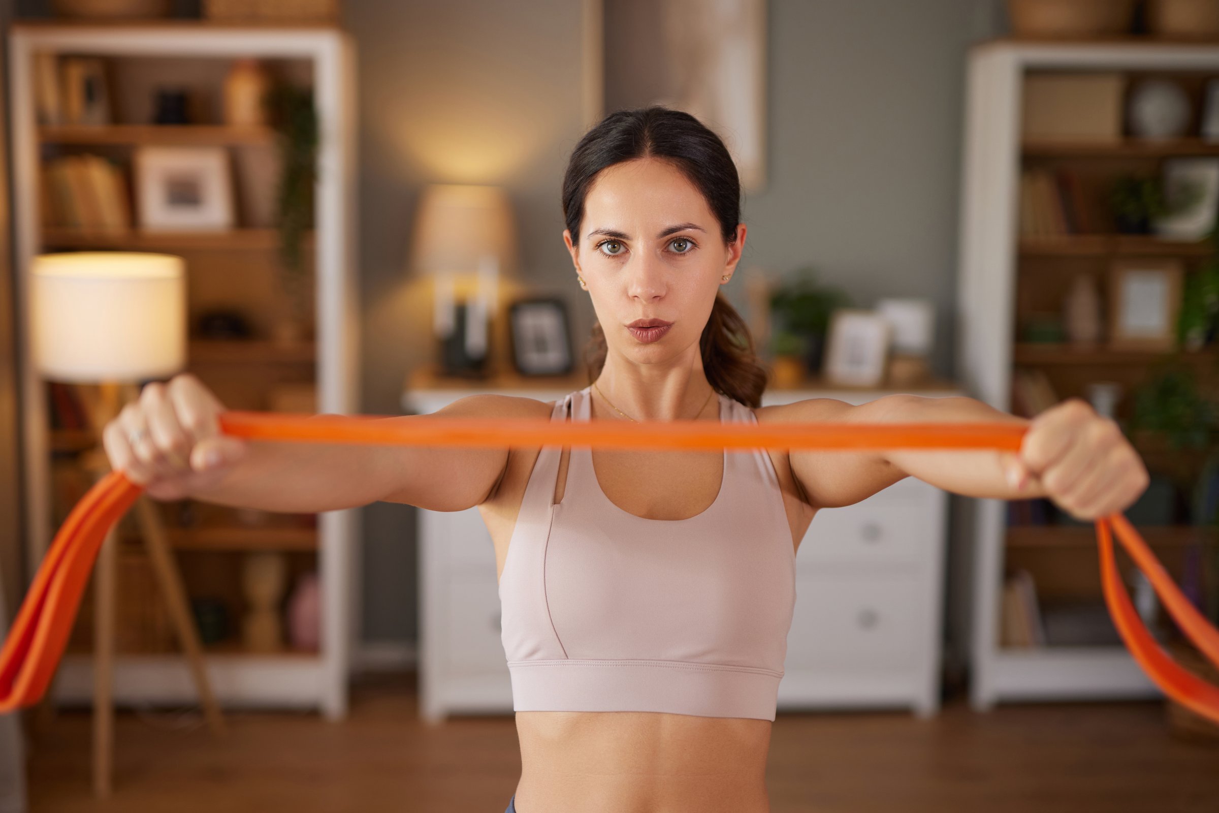 Woman performing arm exercises with a resistance band in her living room