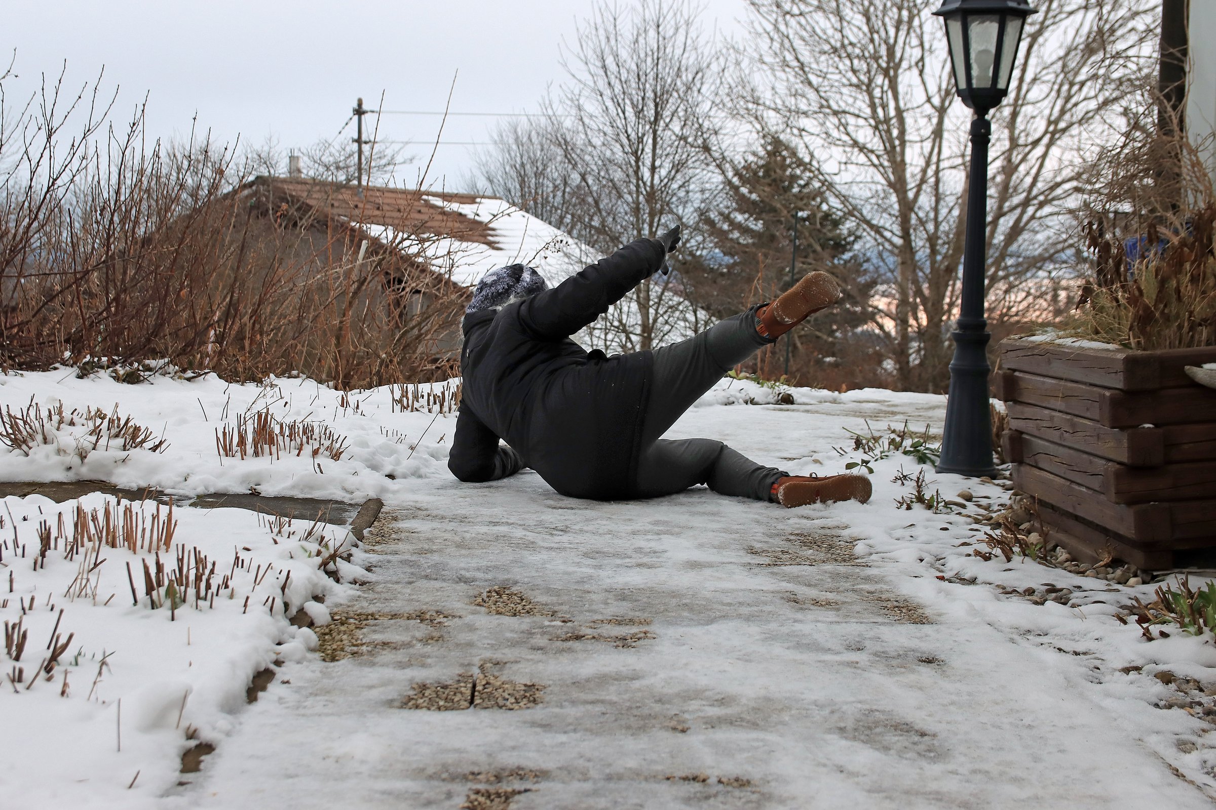 Risk of slipping on a slippery sidewalk in winter. A woman slipped and fell on the ice