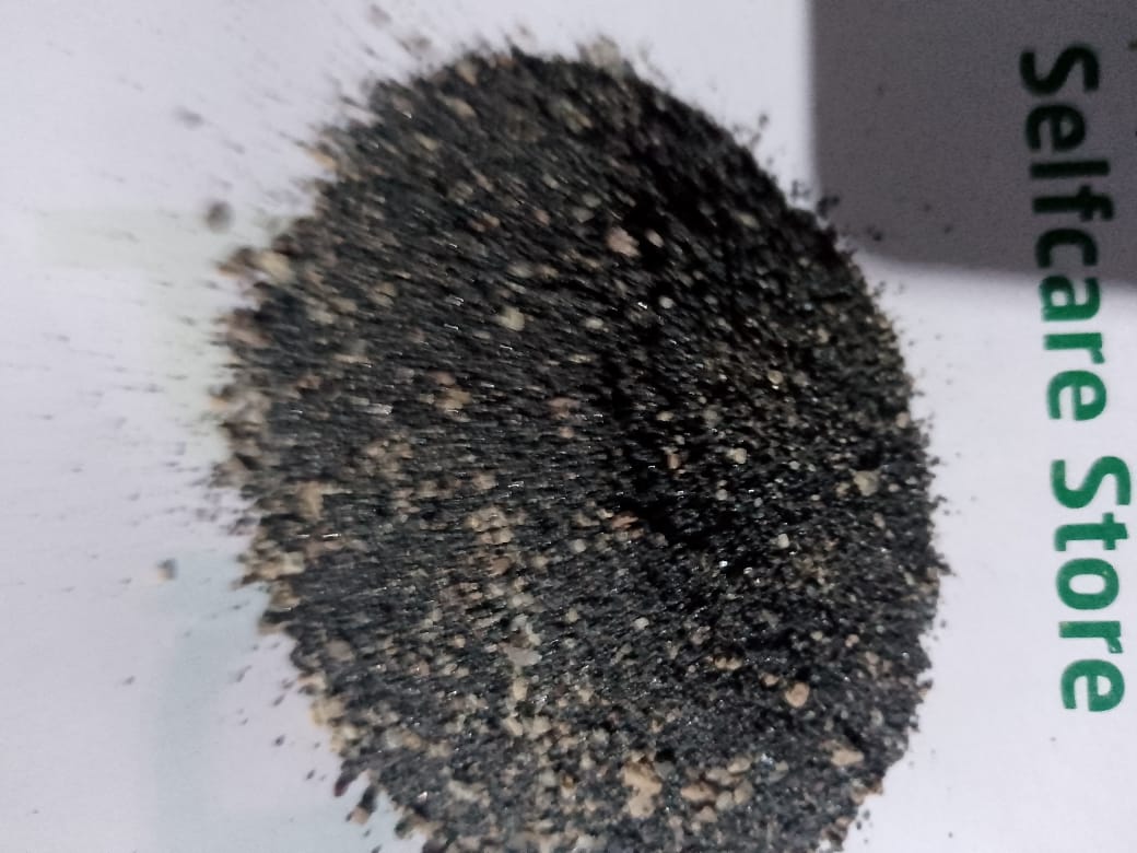 A close-up of a mound of finely ground, dark-colored grains on a sheet labeled "Selfcare Store."