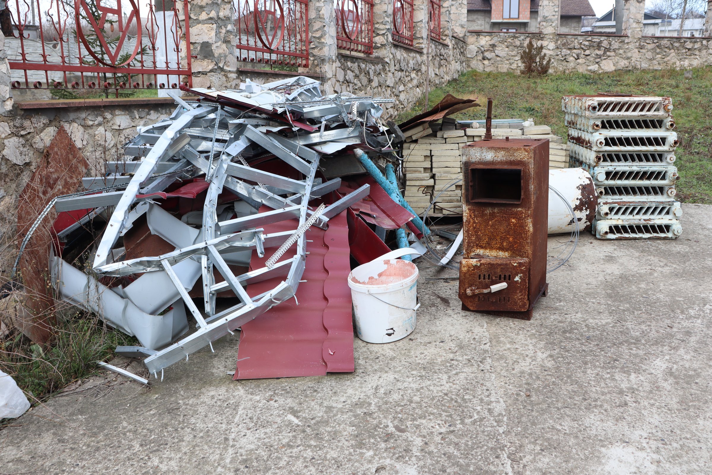 A large collection of abandoned and discarded metal along with wooden materials found in a neglected outdoor area