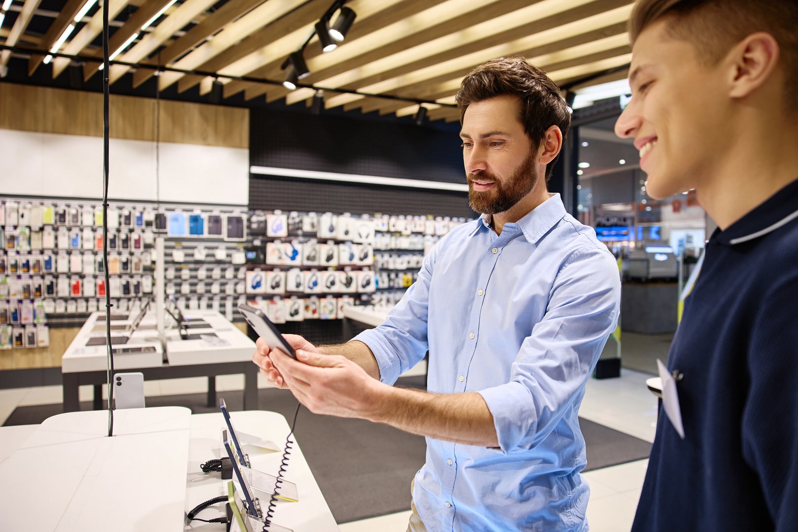 In a modern retail setting, a customer enthusiastically talks with an informed salesperson about the latest smartphones, emphasizing the value of personalized service during their interaction