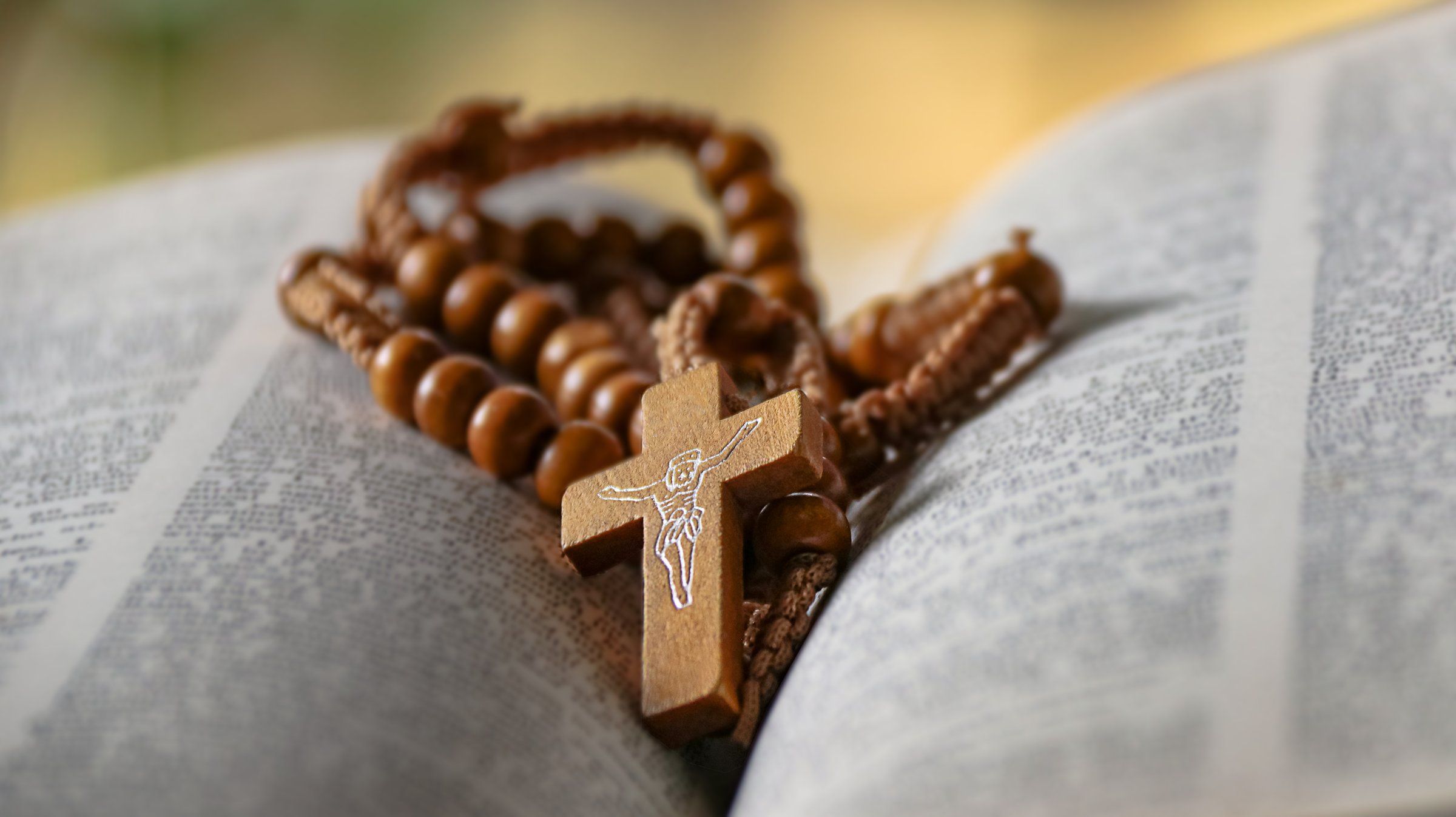 Dark brown wooden cross on an old open book symbolizing the spread of Jesus Christs love among Christians reflecting faith devotion and the importance of Christian teachings.
