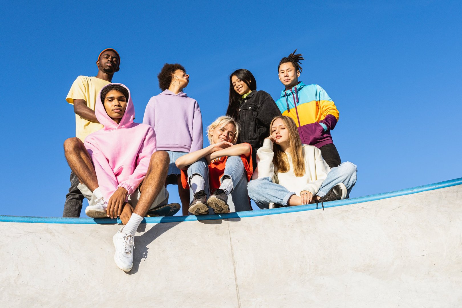 Multicultural group of young friends bonding outdoors and having fun - Stylish cool teens gathering at urban skate park