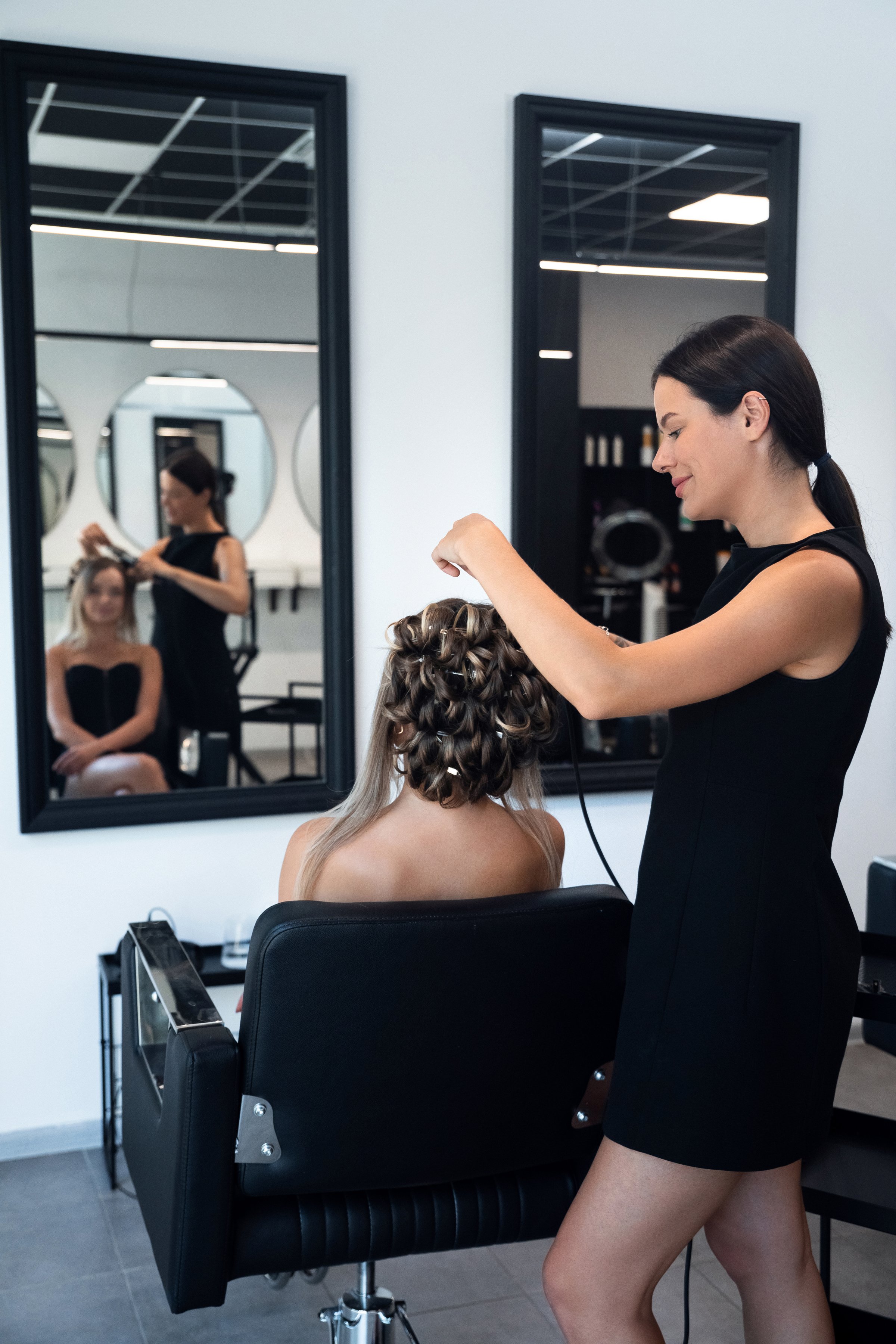 A skilled stylist is arranging a sophisticated hairstyle for a client in a modern salon. The atmosphere is bright and chic, perfect for beauty transformations.