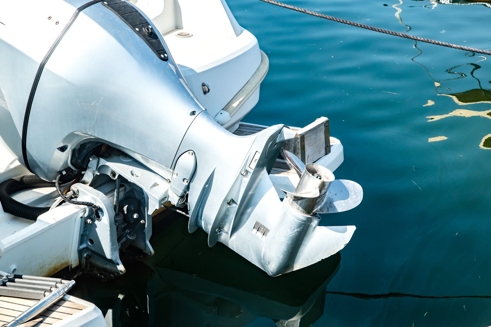 Close-up detail of outboard motor and propeller on docked marine boat, elevated above the water