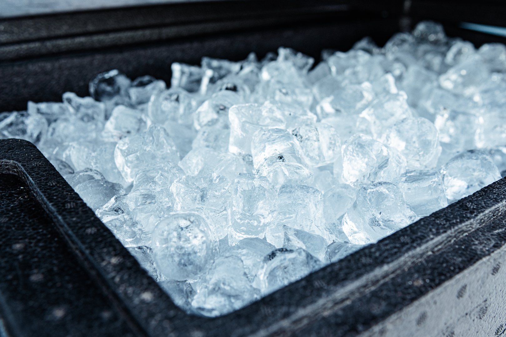 A close-up view of a container filled with clear ice cubes, showcasing their frozen texture and cold freshness