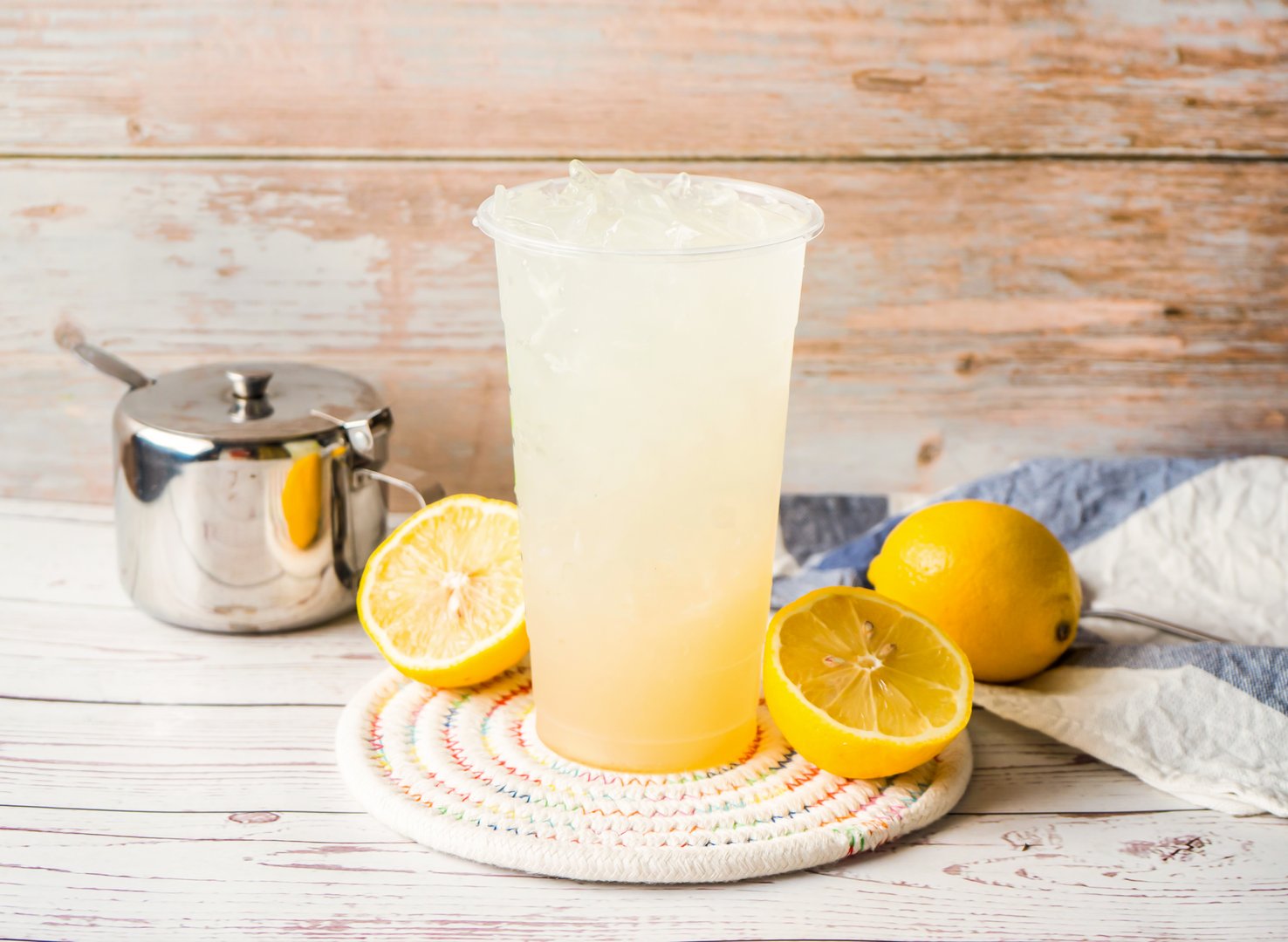 Iced Light Lemon Juice with sugar pot and spoon served in disposable glass isolated on table side view of hong kong tea