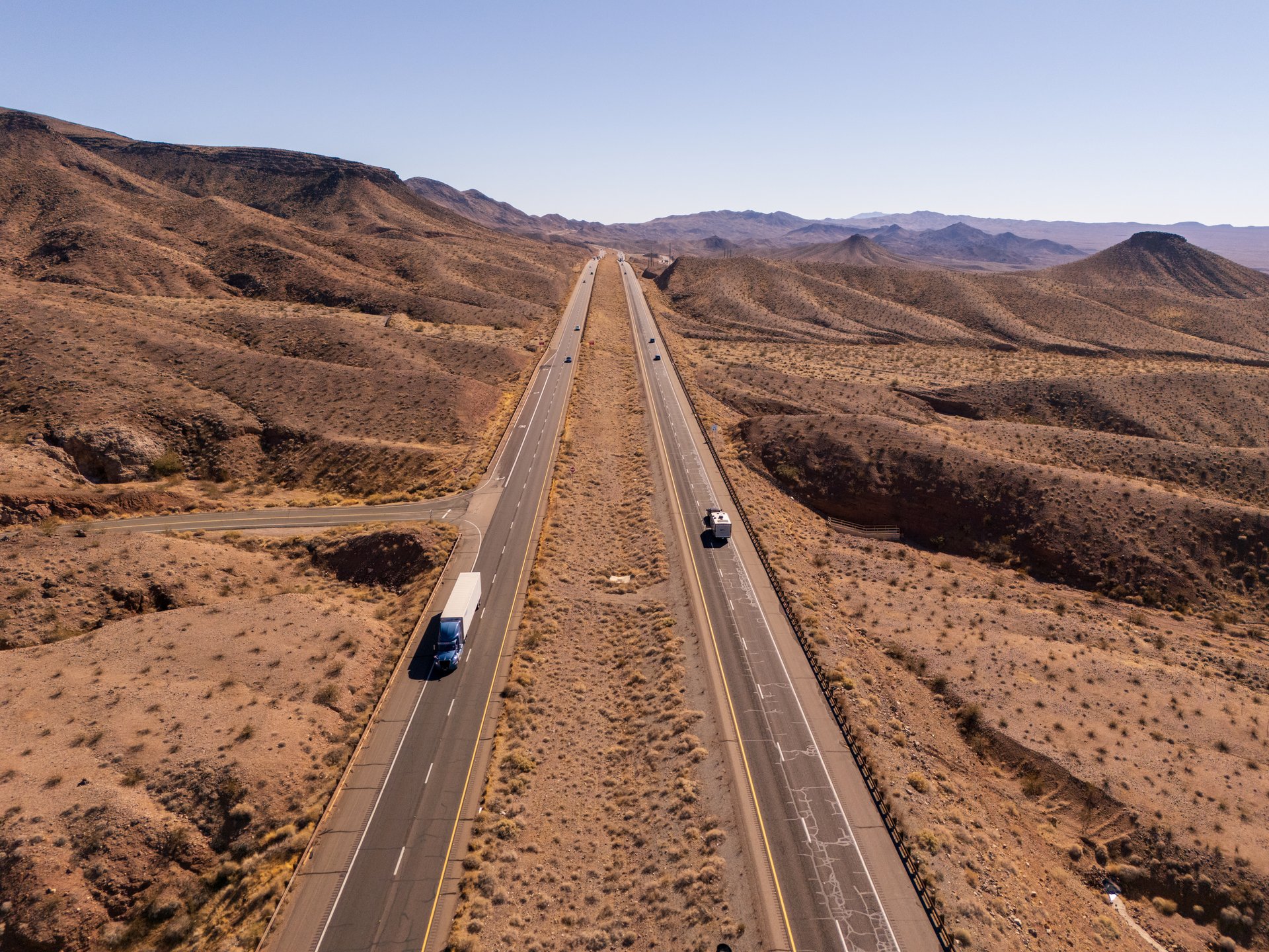 American highway US-93 in a desertic landscape, aerial view, in Arizona. Hills and mountains, cars and trucks driving by