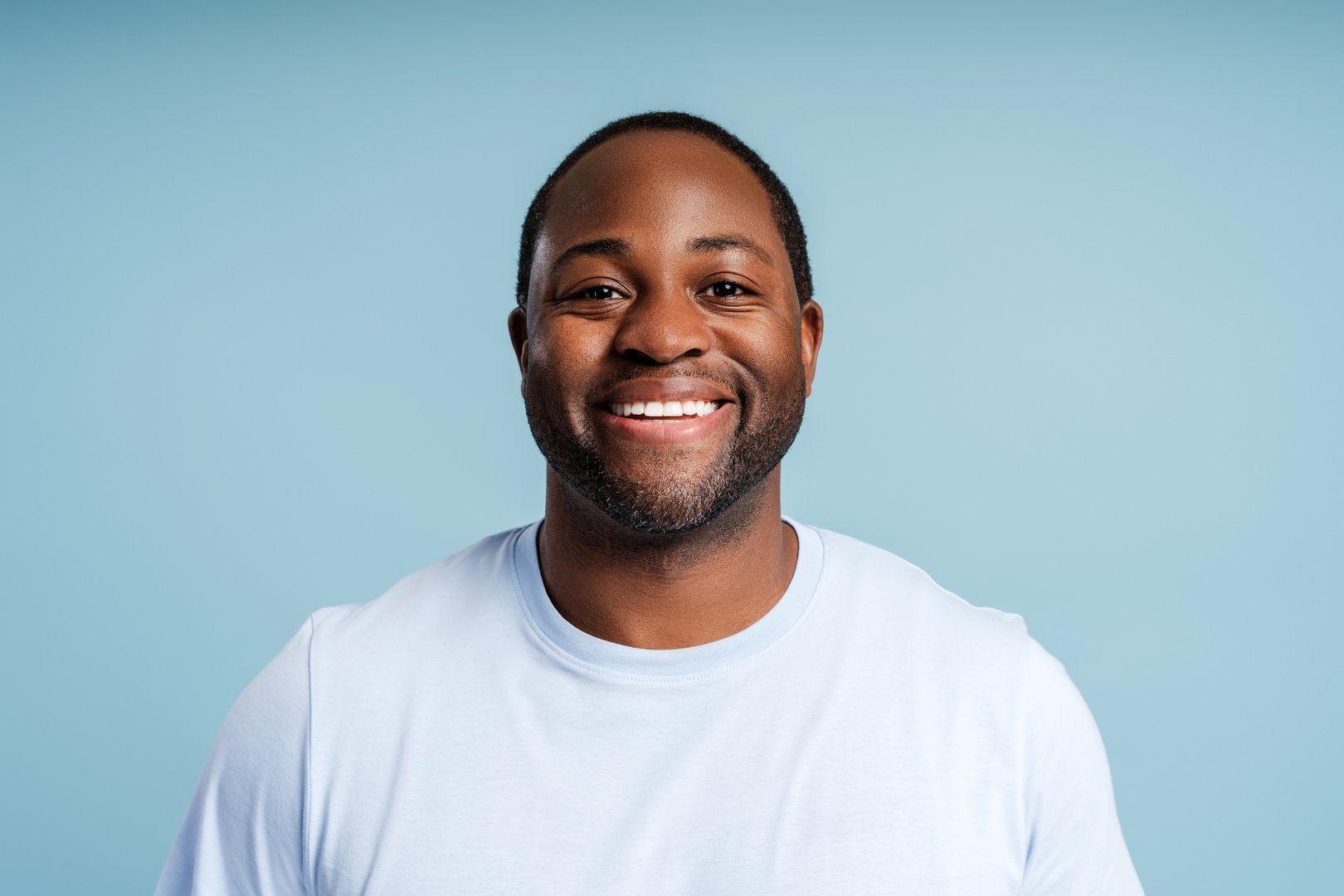 Portrait of African American young man posing at camera, isolated on blue background