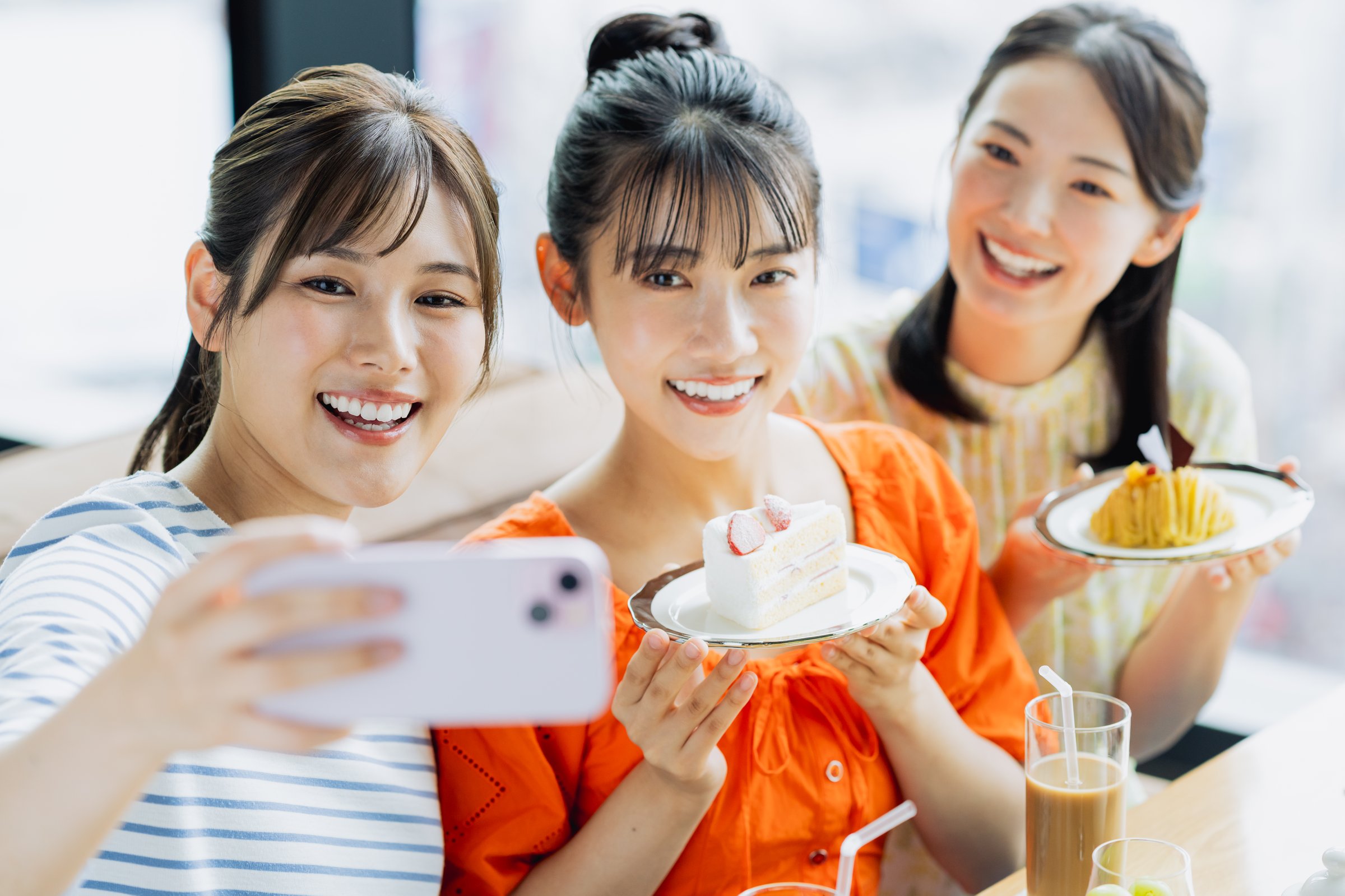 Young woman taking a photo while eating cake at a cafe