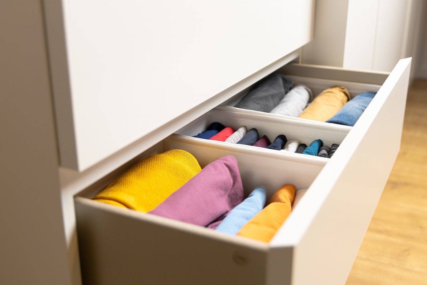 Organized Wardrobe: The photo features neatly folded clothes in dresser drawers, which emphasizes order and minimalism.