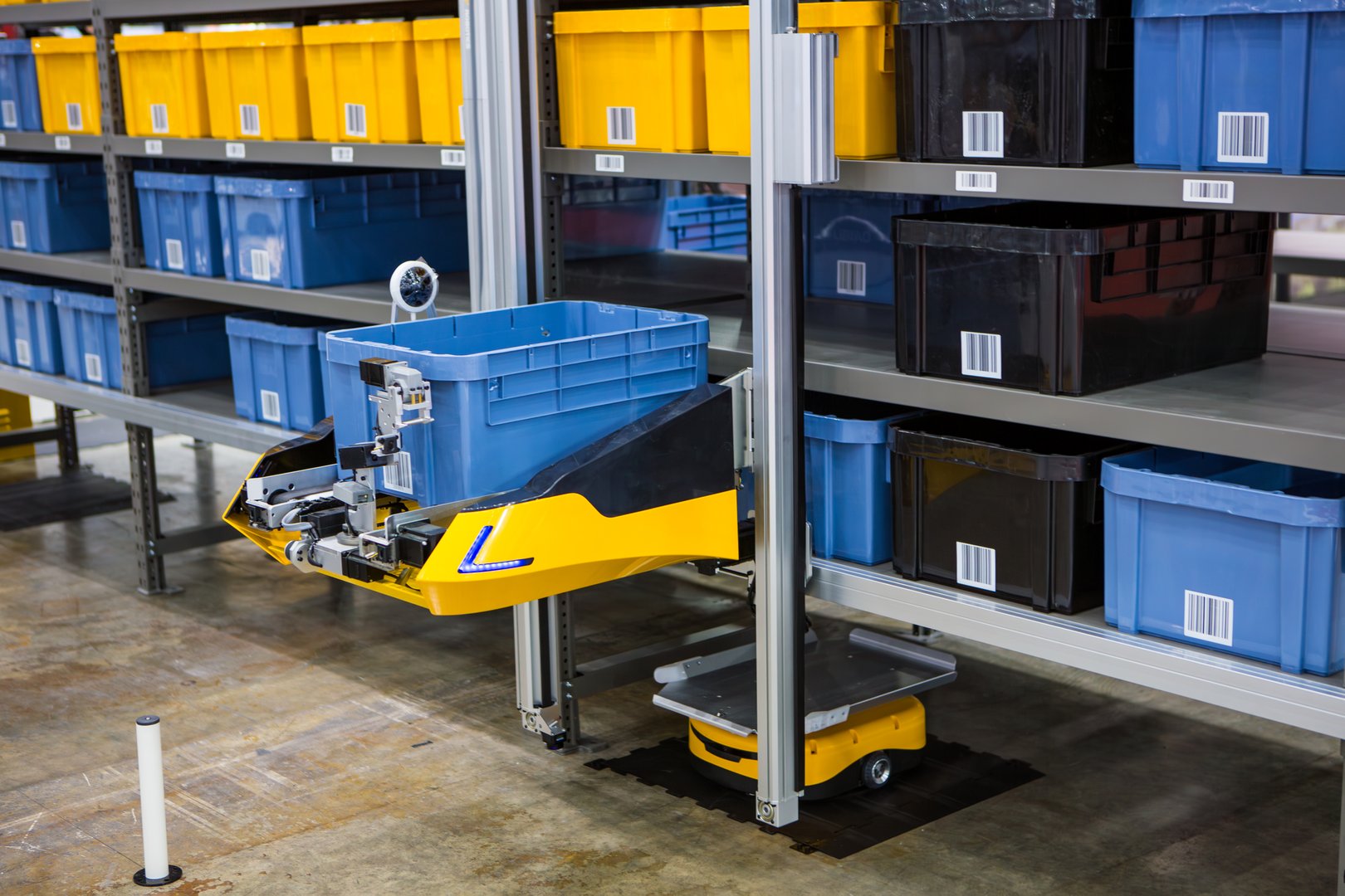 Autonomous robot picking materials from multi-layer rack in modern industrial warehouse.