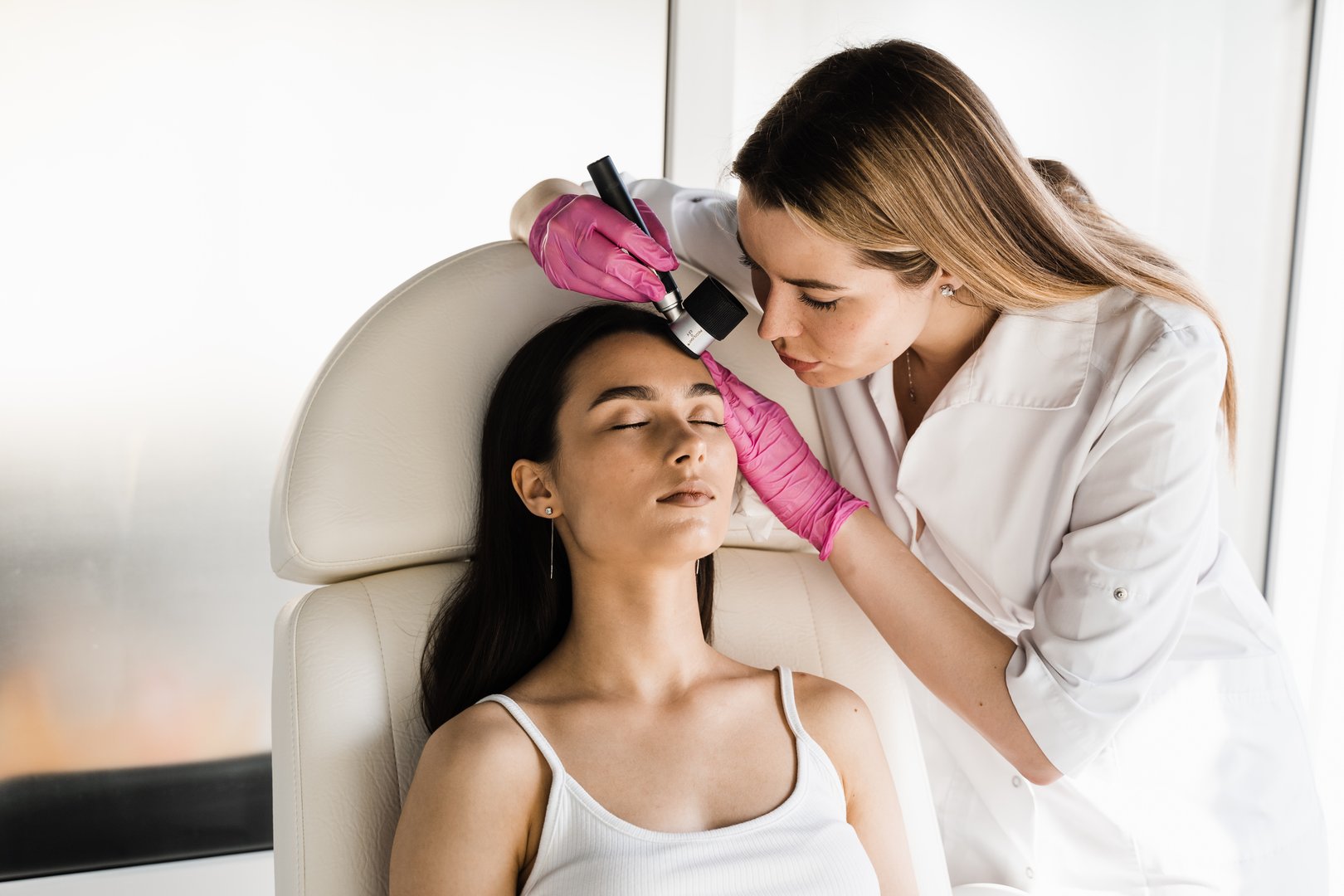 Dermatoscopy of skin lesions and moles with dermatoscope for preventing skin cancer and melanoma. Dermatologist examines moles and birthmarks of girl patient using dermatoscope