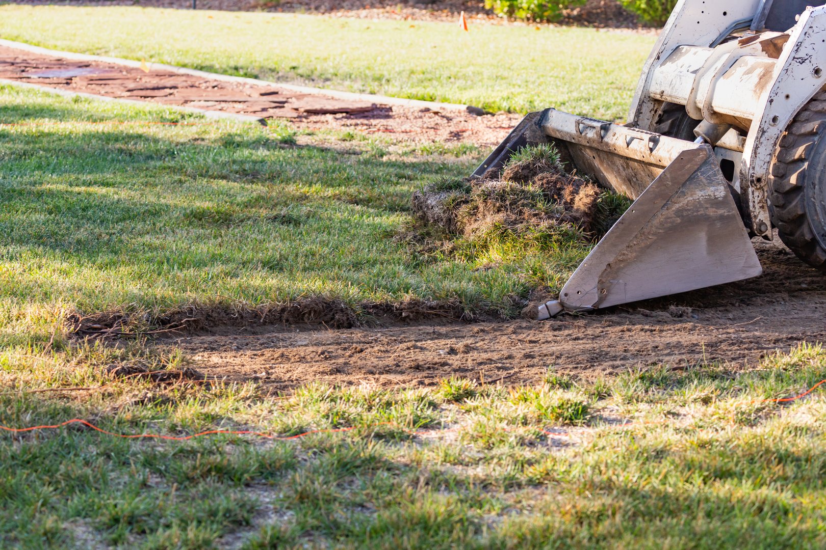 Small Bulldozer Removing Grass From Yard Preparing For Pool Installation