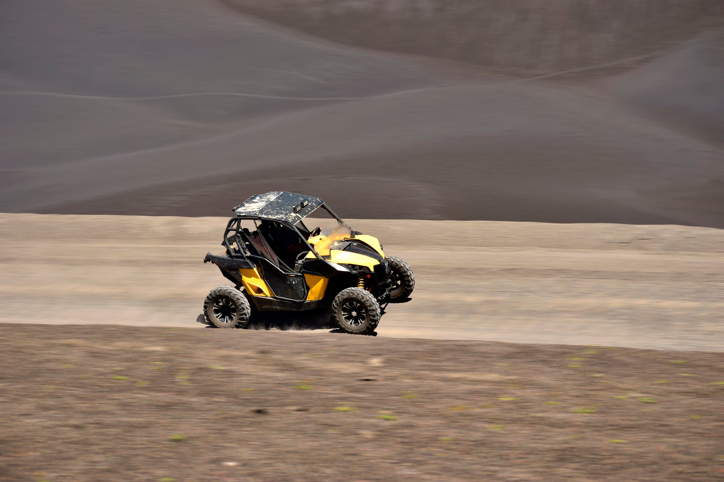 yellow quad bike passing on a desert trail