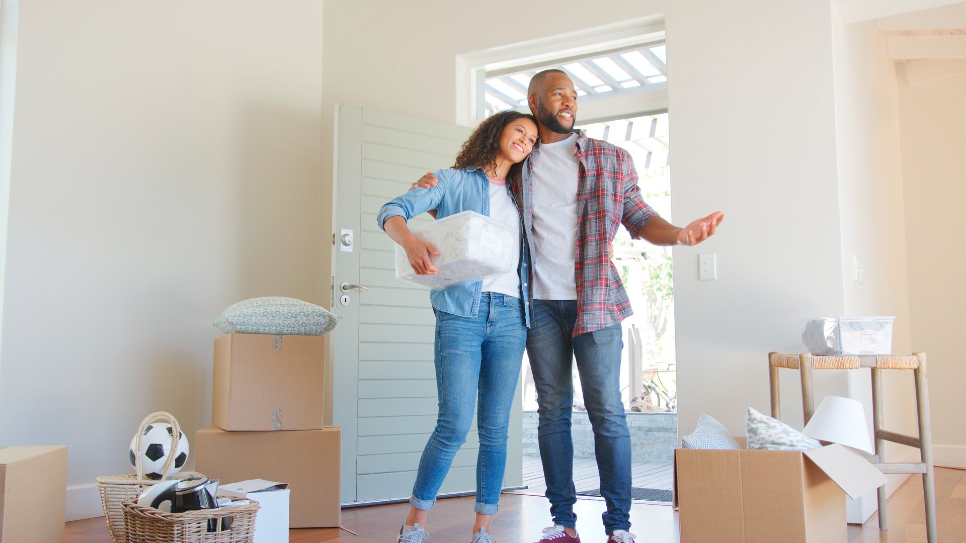 Loving Couple Standing In New Home On Moving Day Surrounded By Boxes