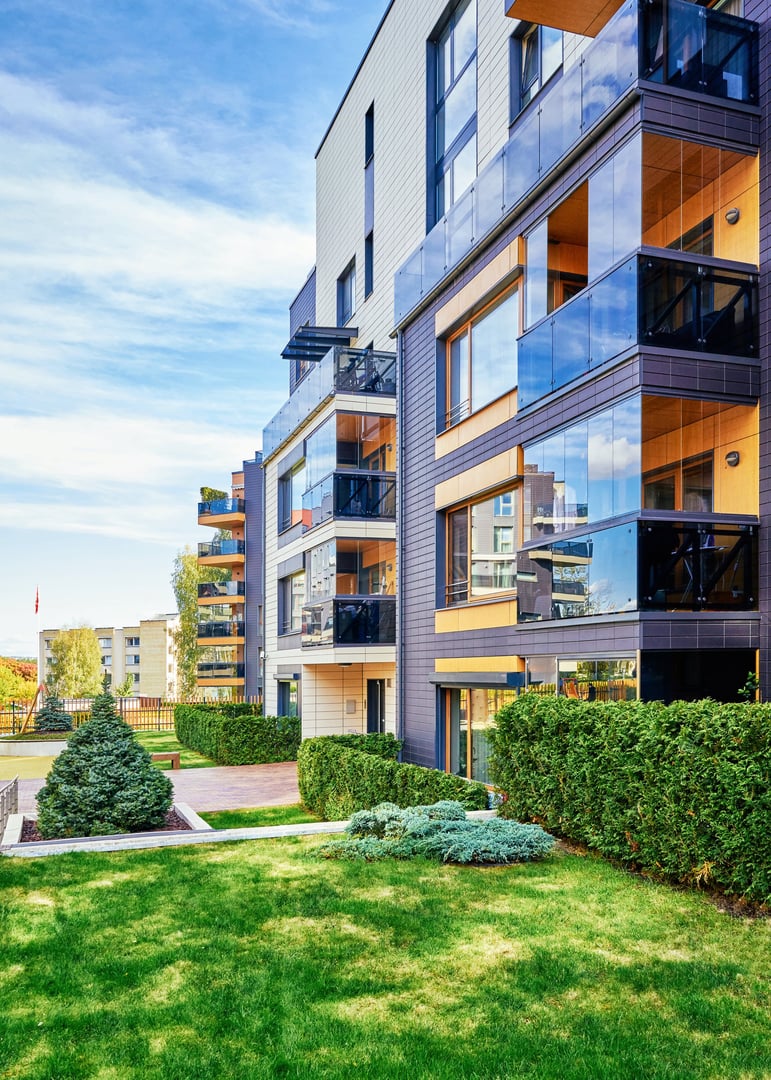 Modern complex of apartment residential buildings with green trees and outdoor facilities.