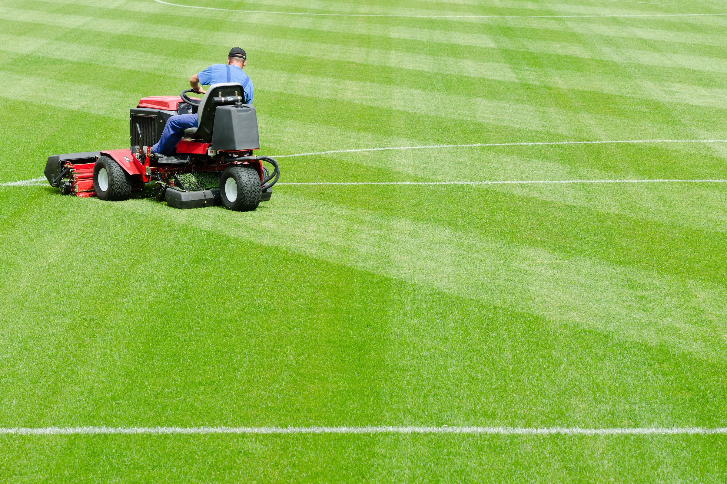 Lubin, Poland August 03, 2011: A man mowing the grass on a football stadium