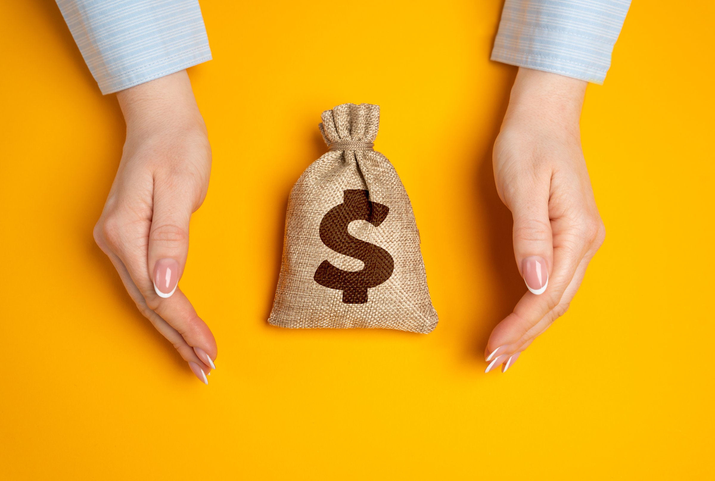 Hands in a gesture of protection of money bag. Concept of capital protection and guarantee of safety of investments and deposits. Financial security. Secure savings