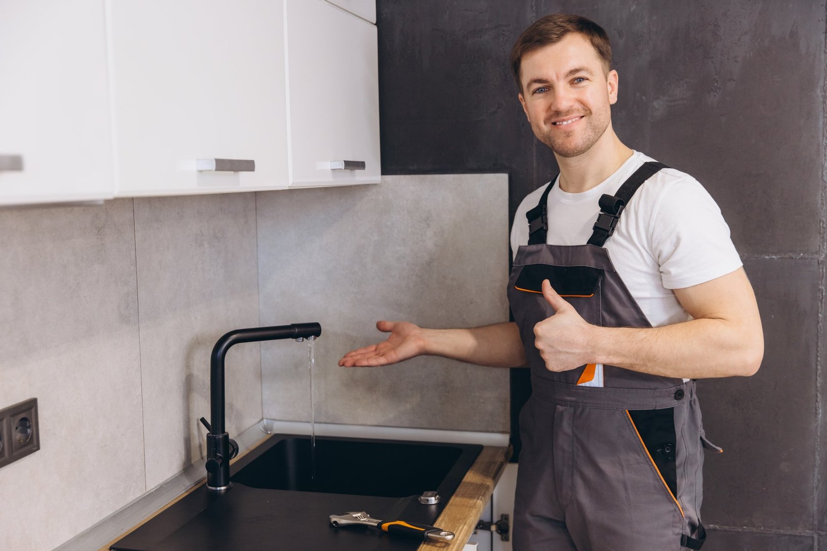 Professional plumber showing his thumb up after successfully installing or repairing a kitchen faucet, ensuring proper water flow