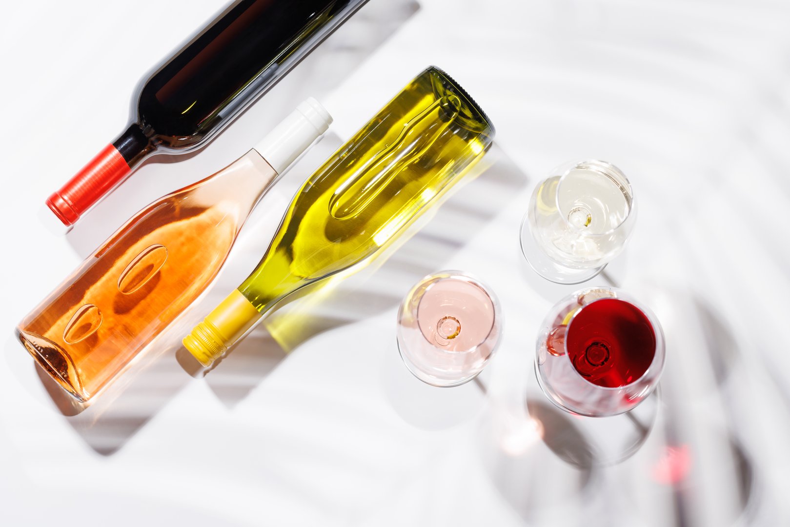 Three wine glasses filled with red, white, and rose wine, standing gracefully on a bright, minimalist background. A vibrant display of wine's variety and elegance