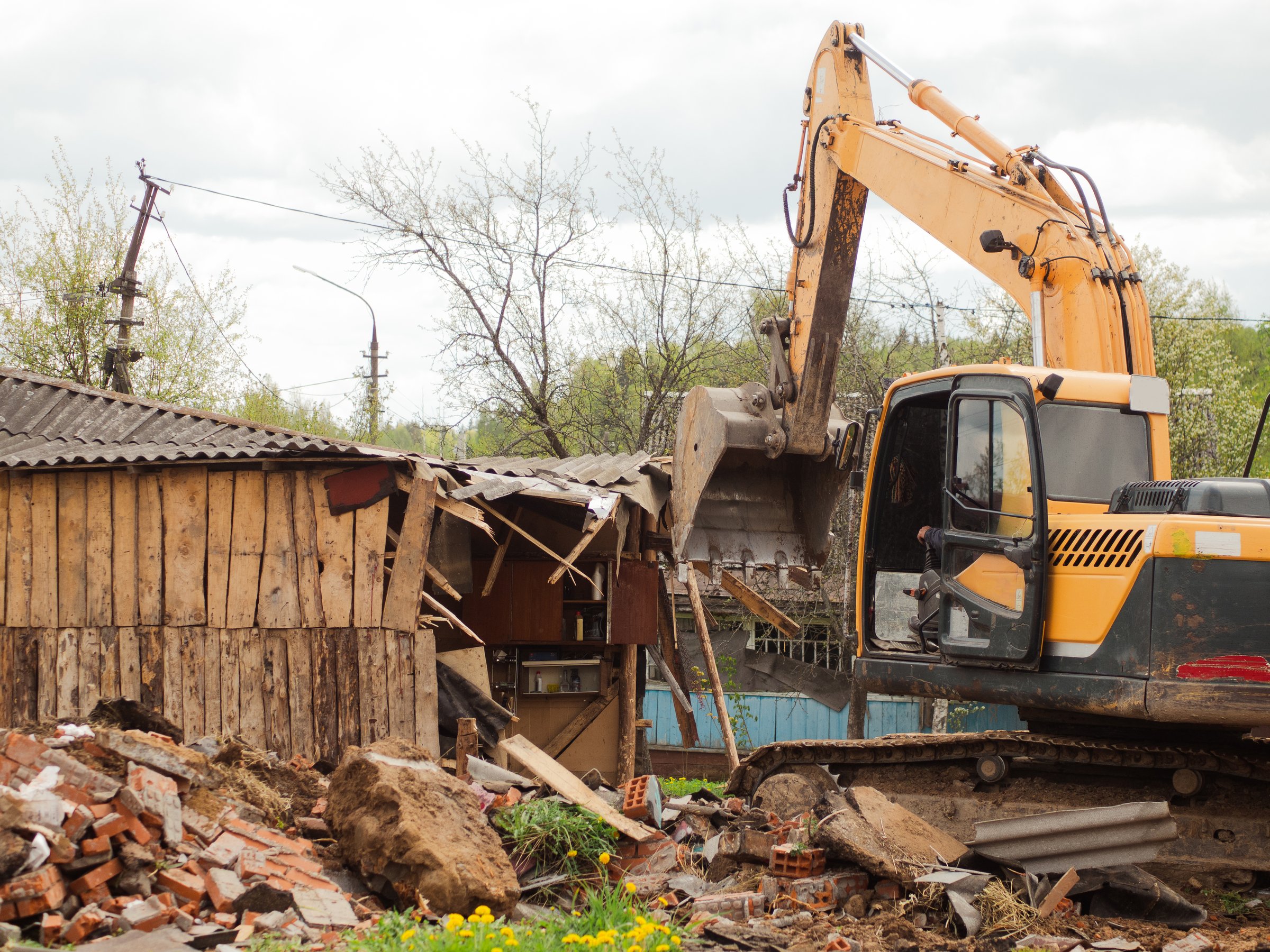 yellow excavator demolishes old buildings with its bucket