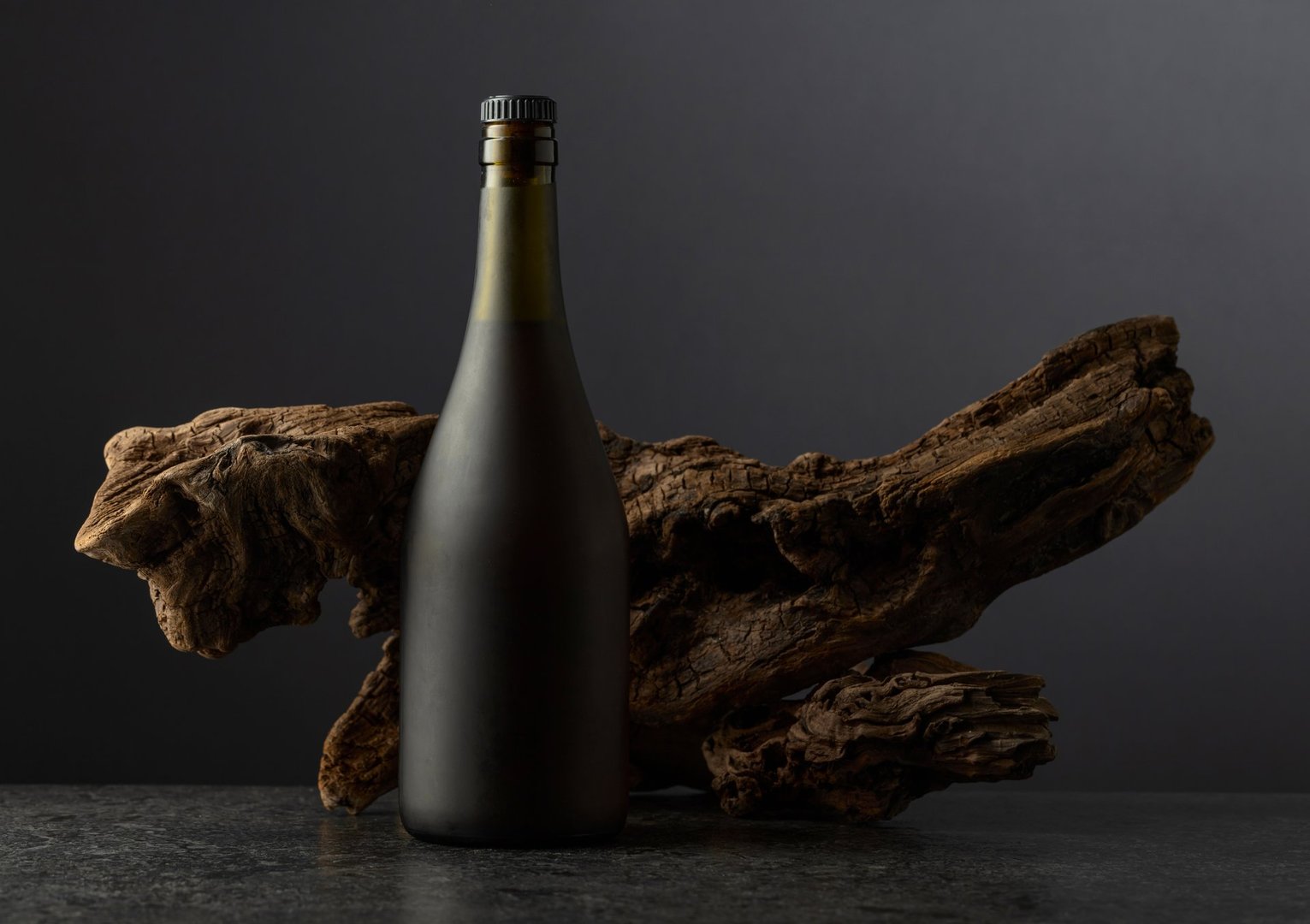 Vintage bottle of brandy and old snag on a black background. Copy space.