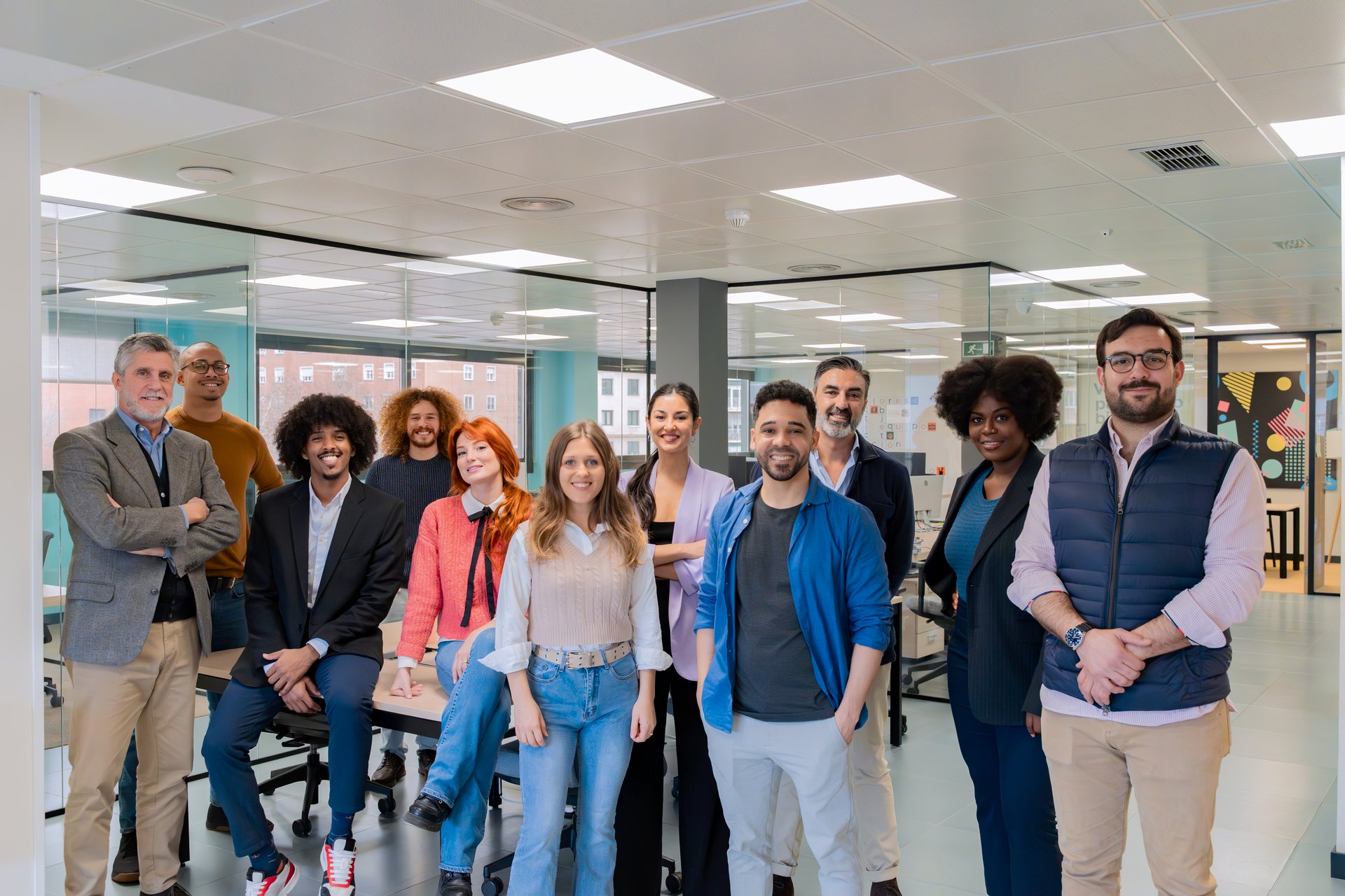 Un grupo diverso de profesionales sonriendo y posando juntos en un espacio de oficina contemporáneo.