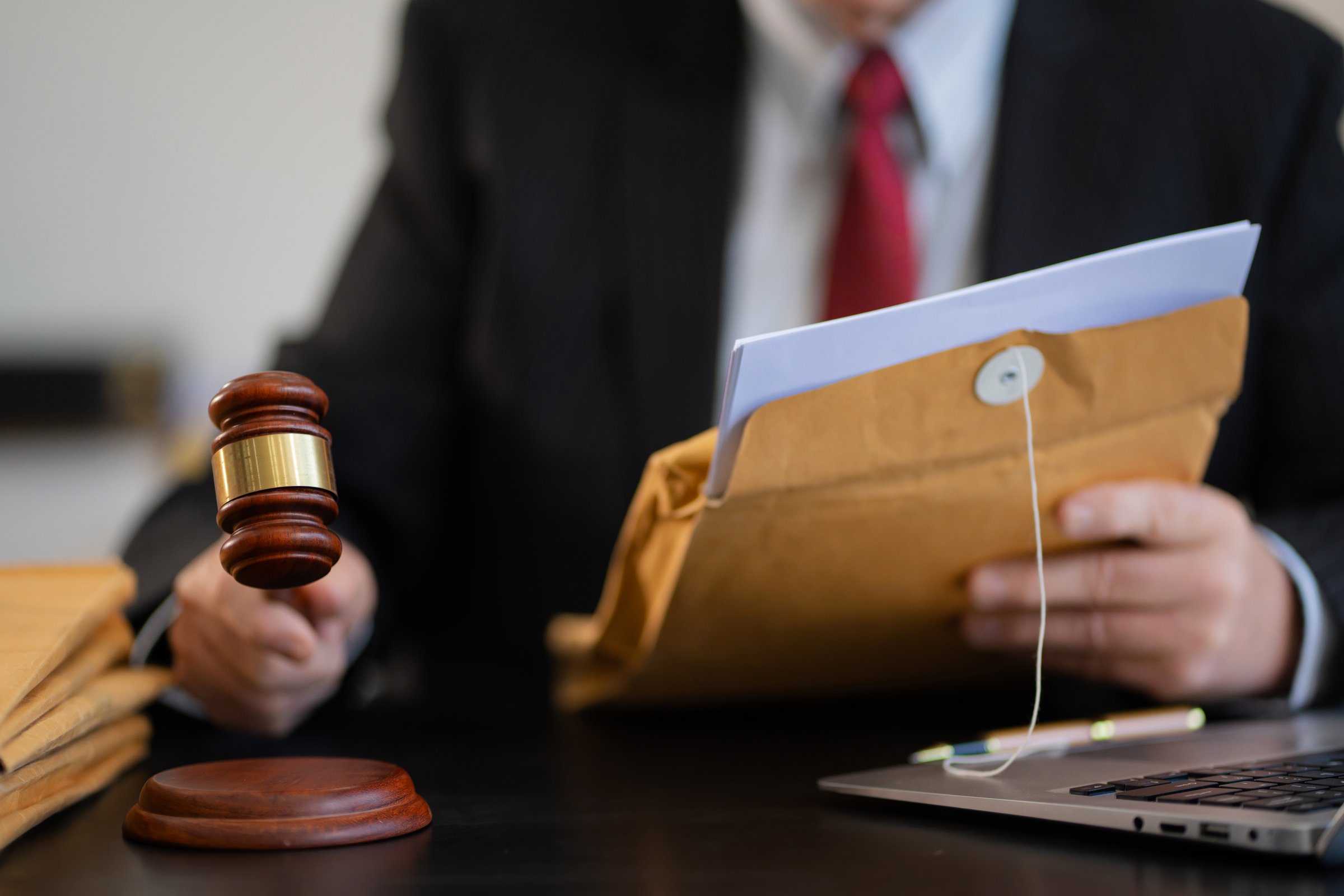 Justice and law concept.Male judge in a courtroom the gavel, working with digital tablet computer on wood table.
