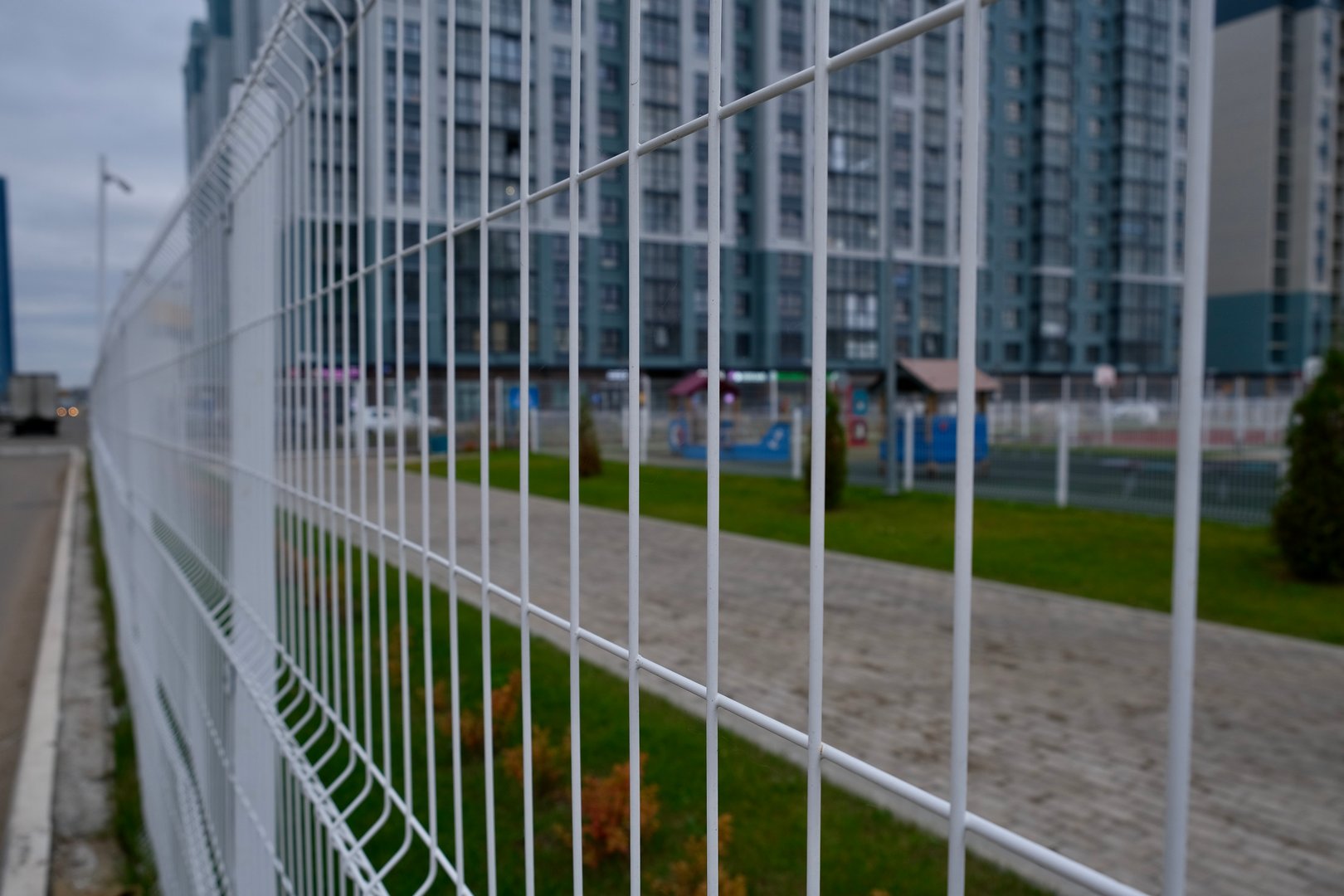A close-up view of a white fence in an urban setting, with modern buildings behind it, showcasing a contemporary city vibe. High quality photo