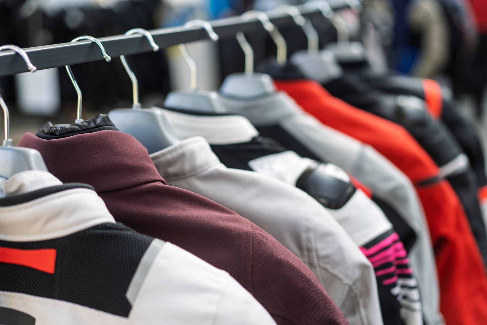 Close-up of colorful motorcycle jackets hanging on a rack in an outdoor market, showcasing various styles and colors, concept for fashion diversity and outdoor shopping experience