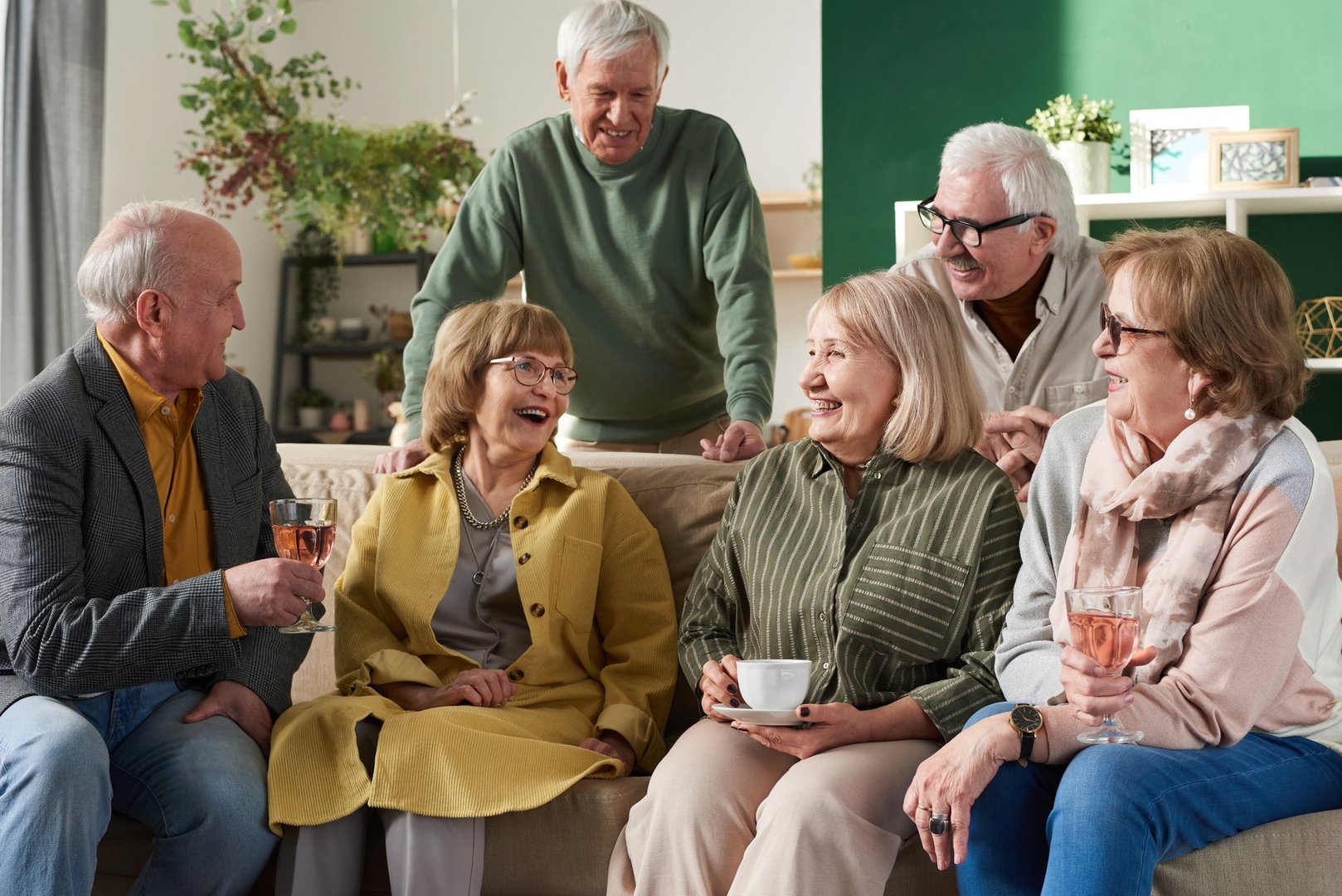 Happy old friends sitting on sofa and talking to each other during meeting in domestic room