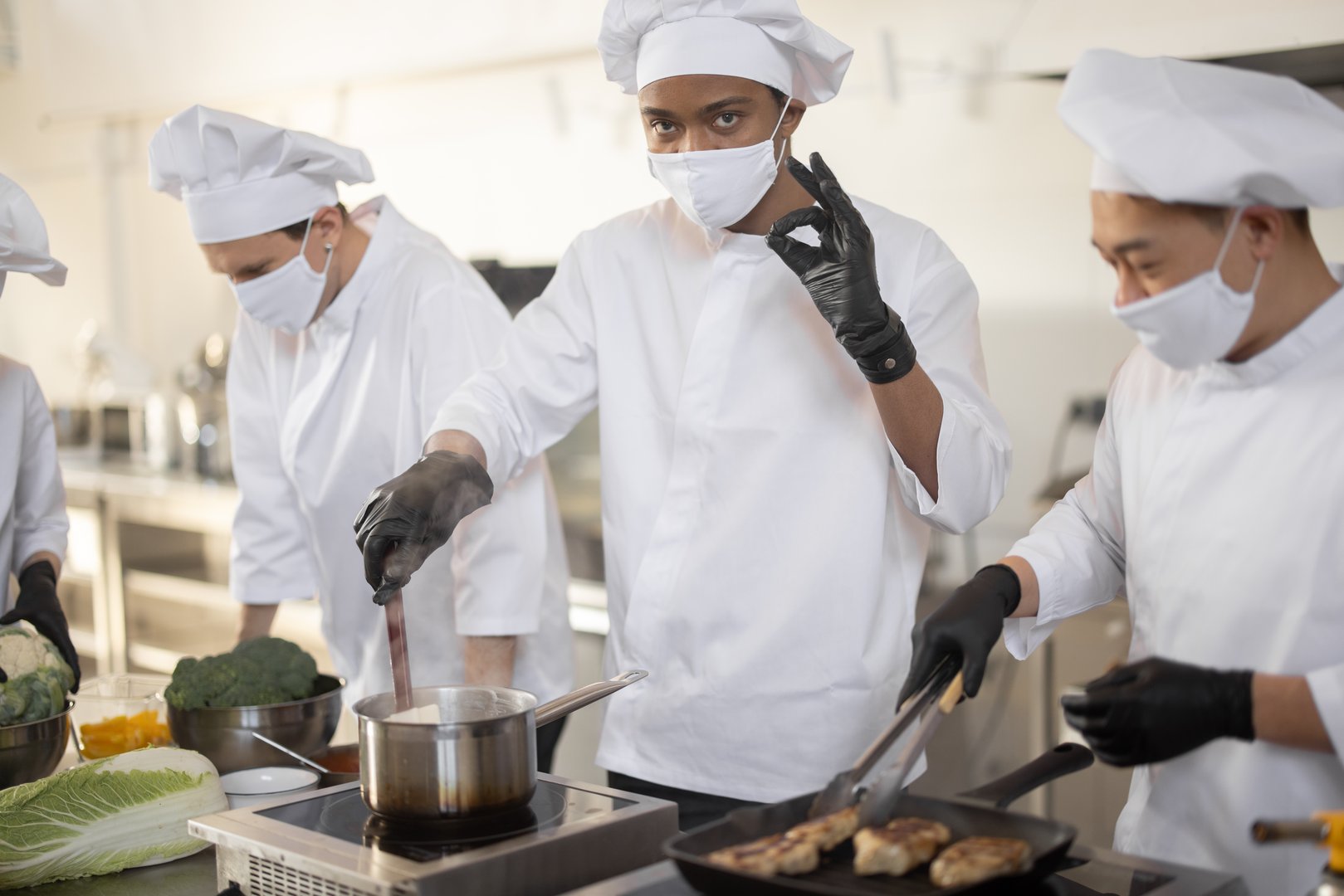 Equipo profesional usando cofias y guantes en cocina industrial