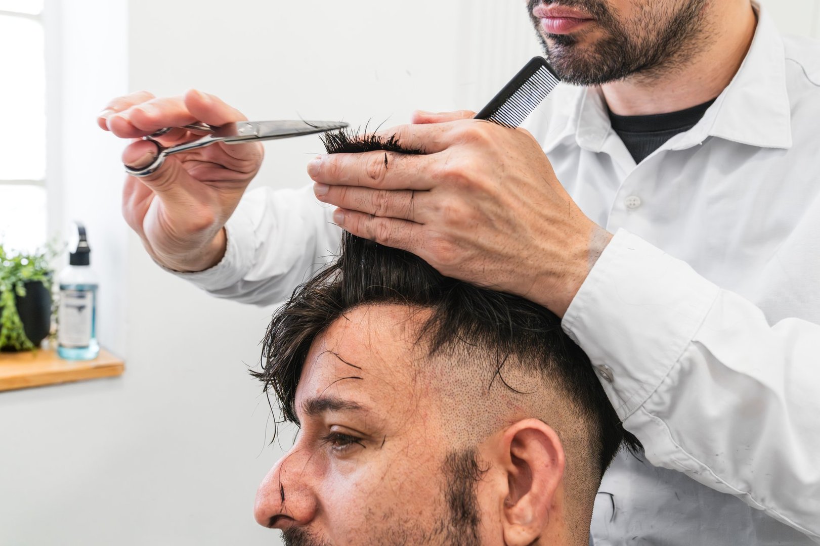 Hair transplant clinic specialist cutting and styling hair of a male customer after a hair implant procedure