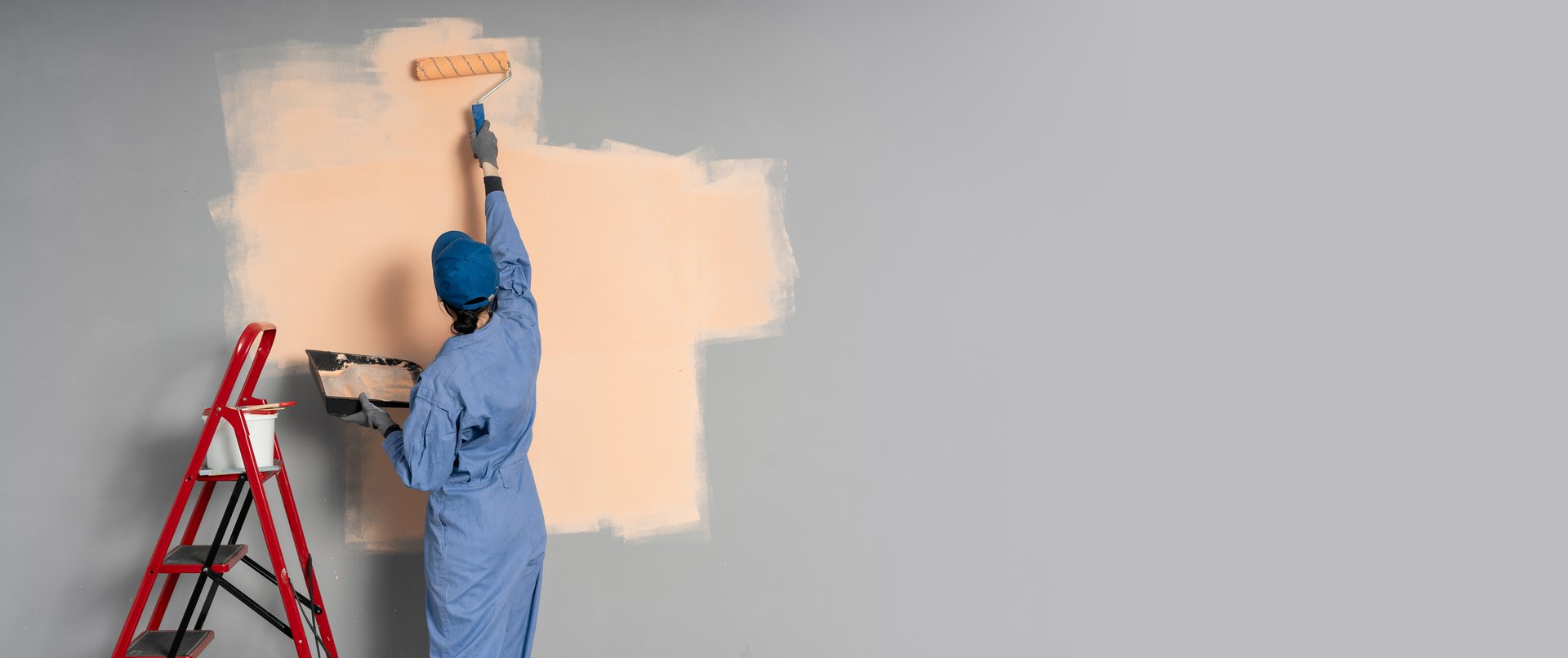 Back view. Painter painting blue wall. Professional builder makes repairs.