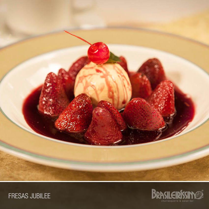 Dessert with strawberries, ice cream scoop, cherry on top, and red sauce in a bowl labeled 'Fresas Jubilee'.