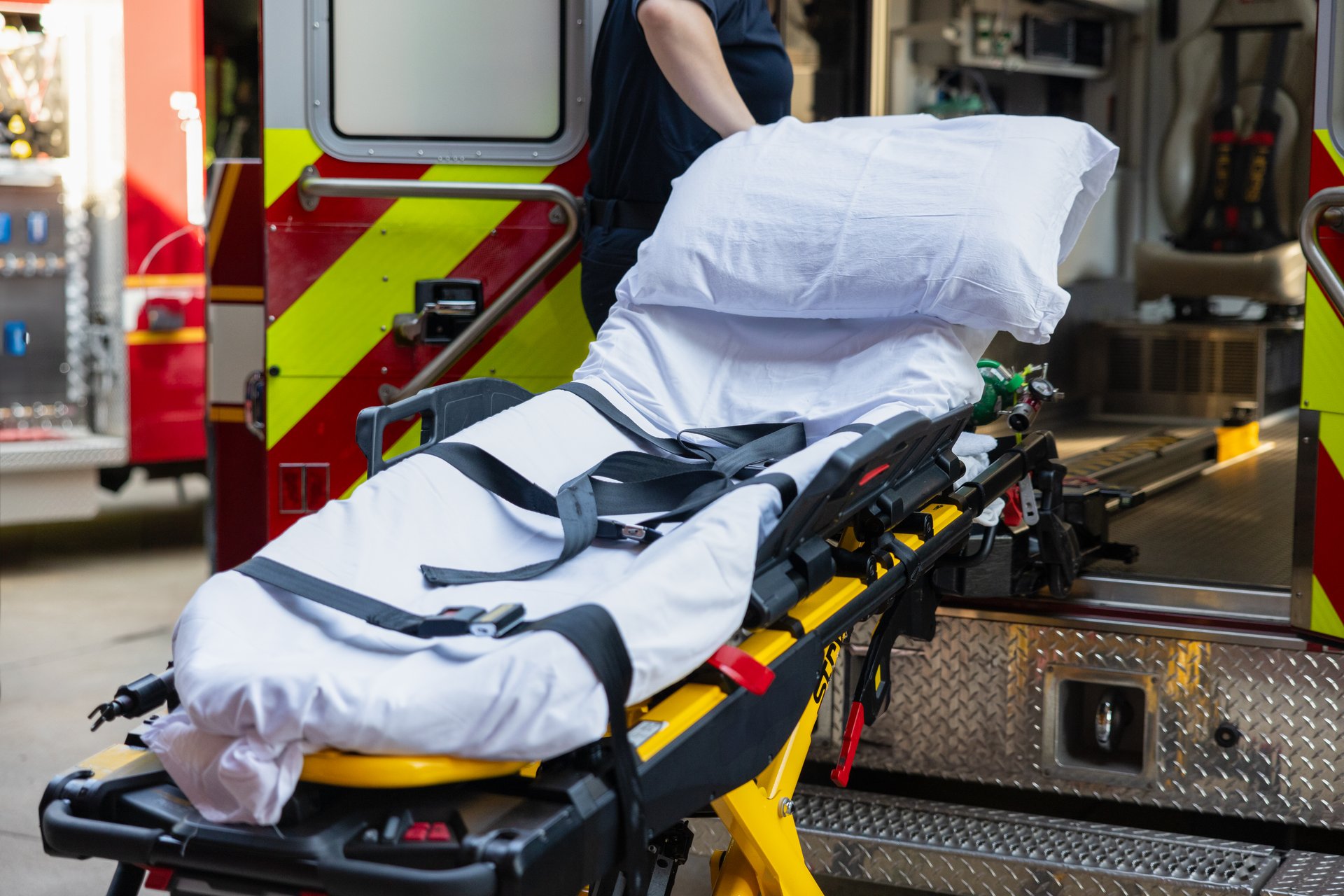 An empty stretcher is loaded into an ambulance