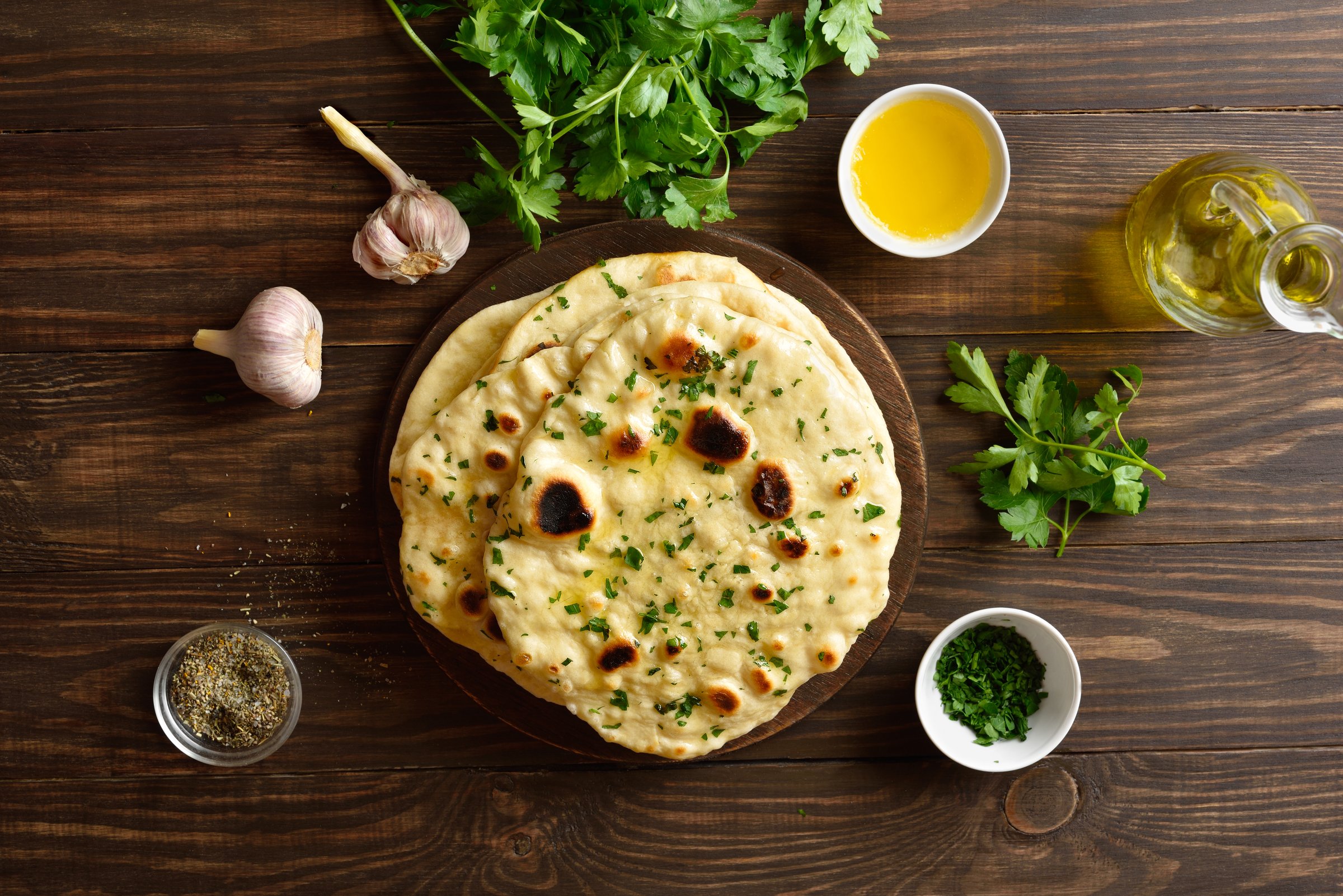 Homemade indian naan bread with garlic butter on wooden background. Top view, flat lay