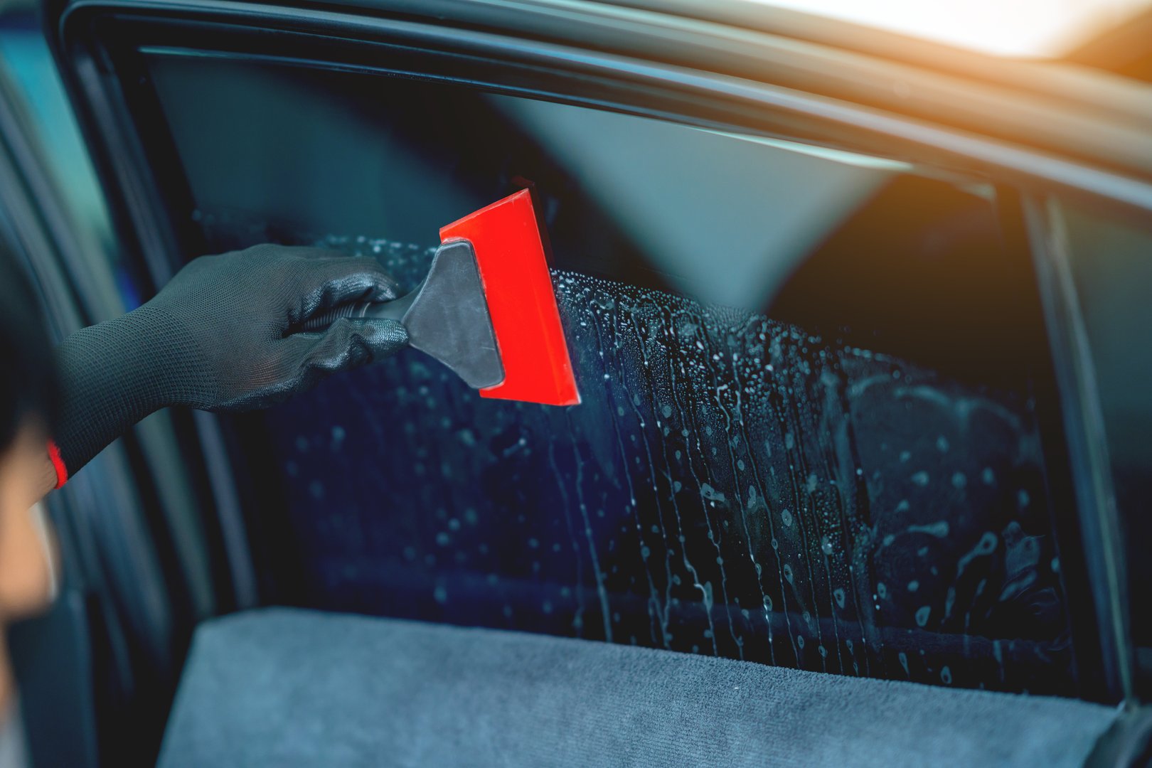 Technician uses equipment to install car window film.