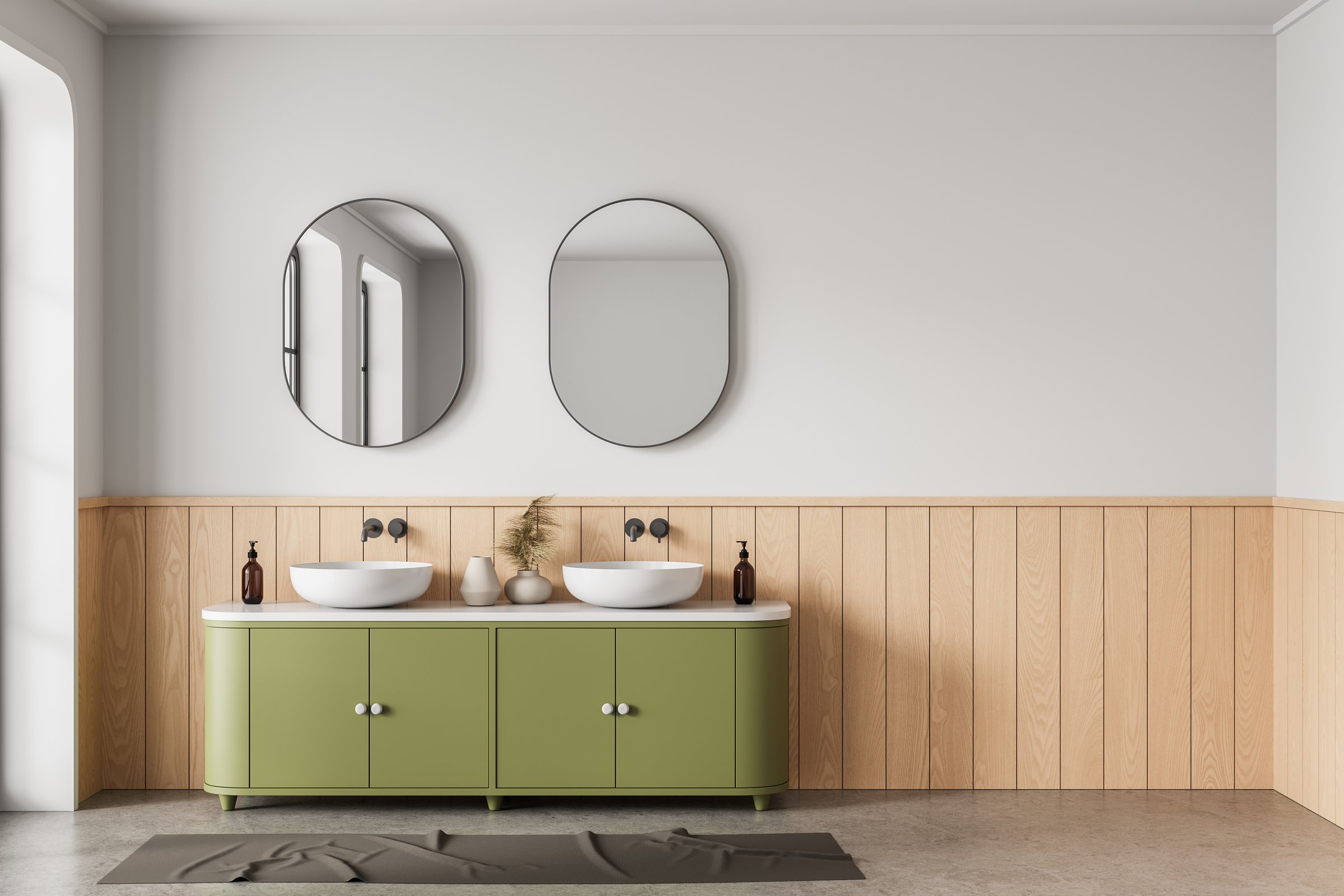 Contemporary bathroom interior with olive green vanity, two vessel sinks, oval mirrors, and wood paneling on light wall. 3D Rendering