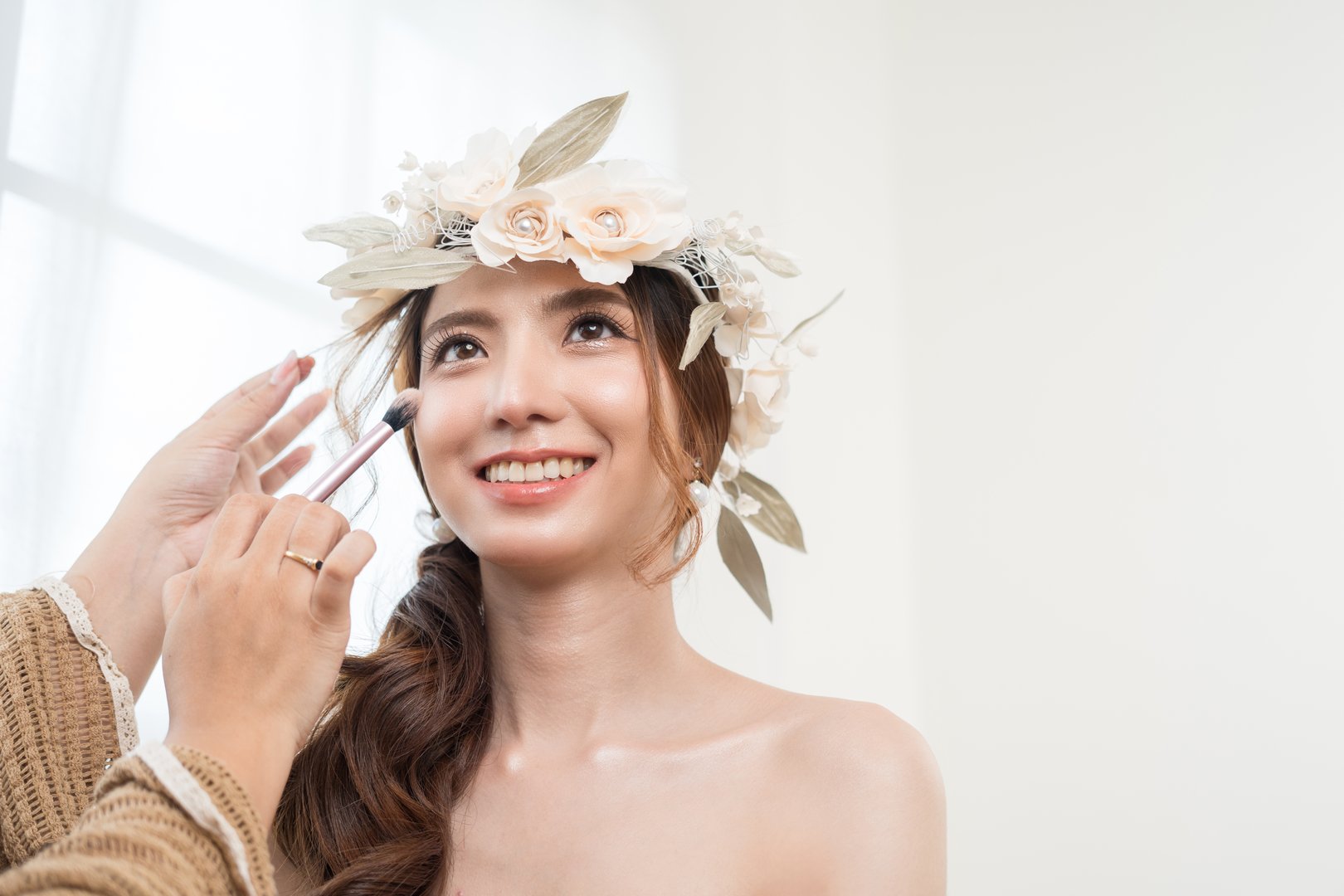 Beautiful young asian bride with wedding makeup and hairstyle before ceremony. Preparation for wedding applying with cosmetic by artist makeup.