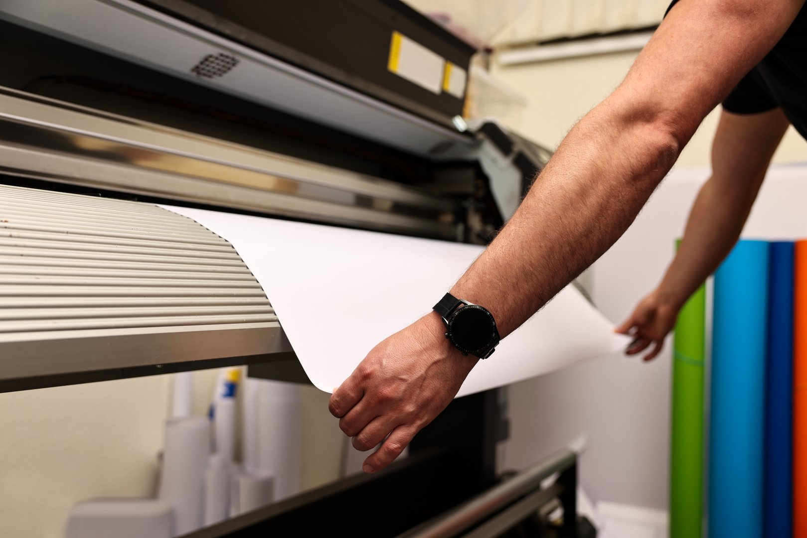 Man using wide-format printer indoors, closeup. Printing house