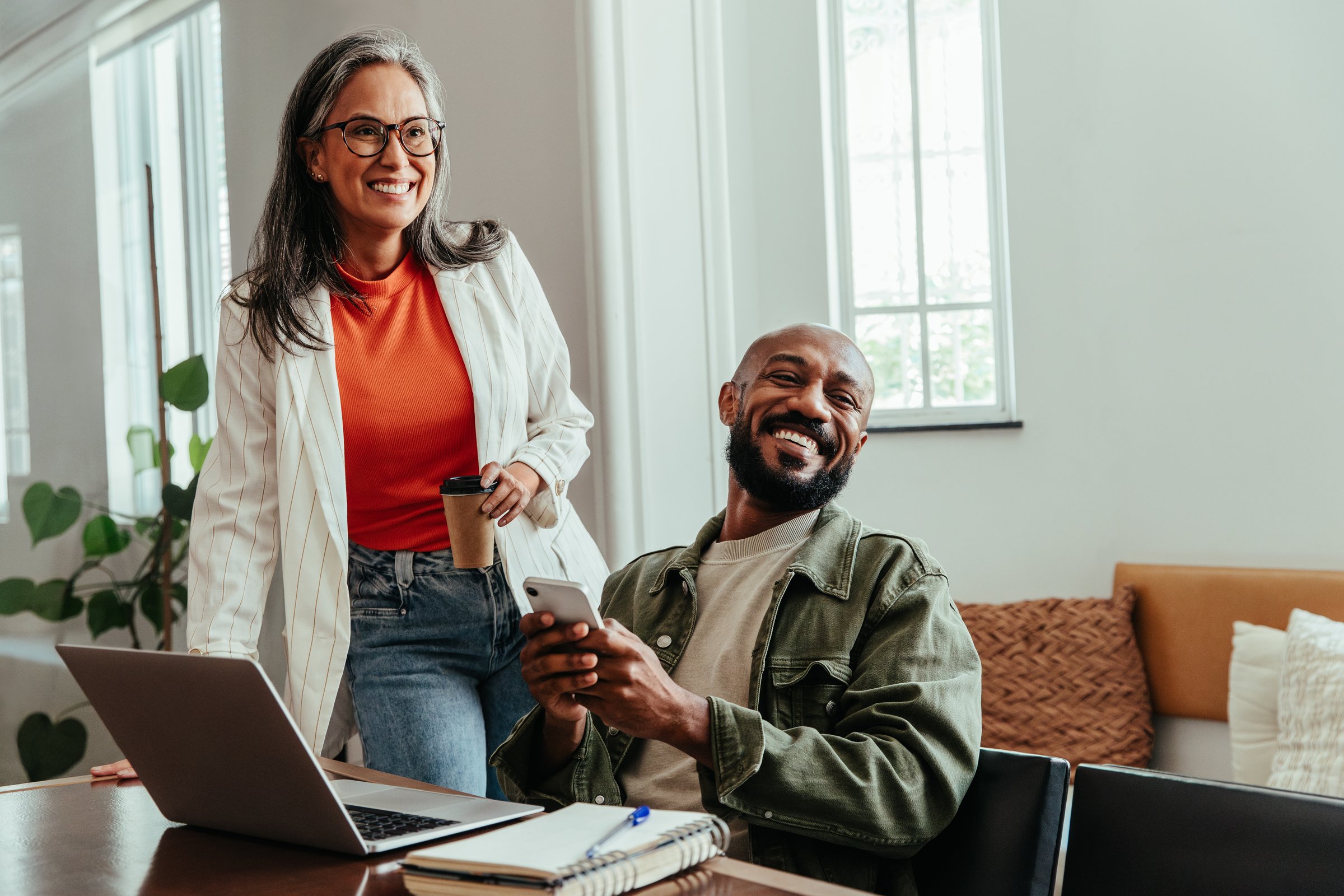 Colleagues having a casual discussion in a co-working office environment, featuring a smiling manager and a relaxed atmosphere.