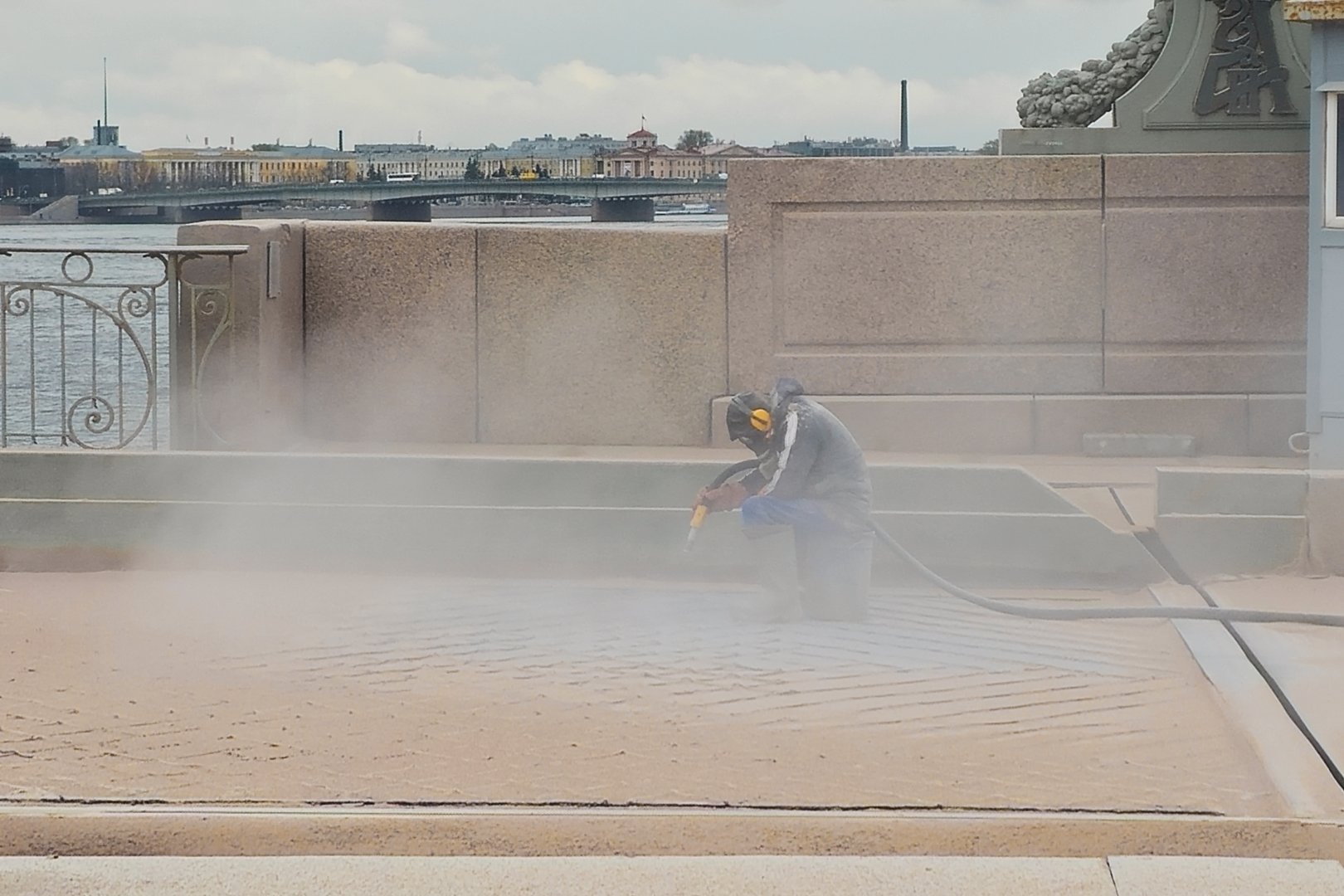 Blast cleaning. An unrecognizable man at work at the bridge construction site, working in the dust. The dusty construction that floats in the air.