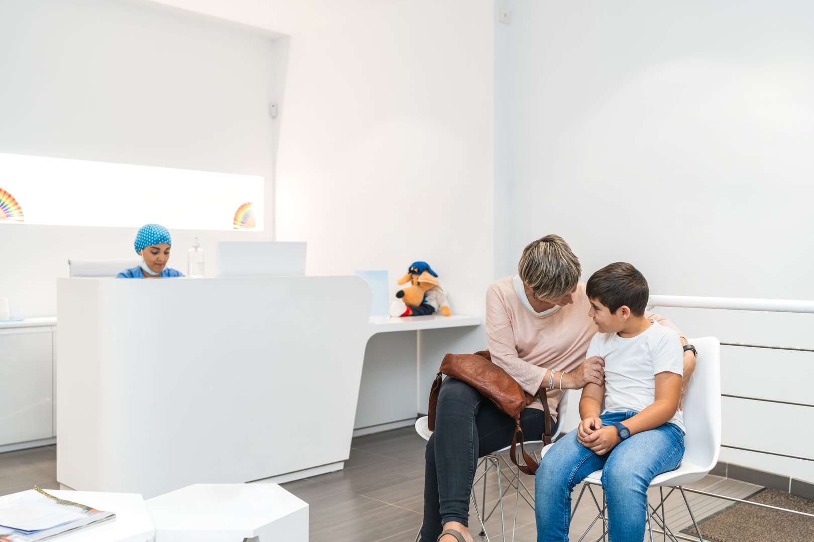 A mother gently comforts her son while waiting in a dental clinic for his appointment