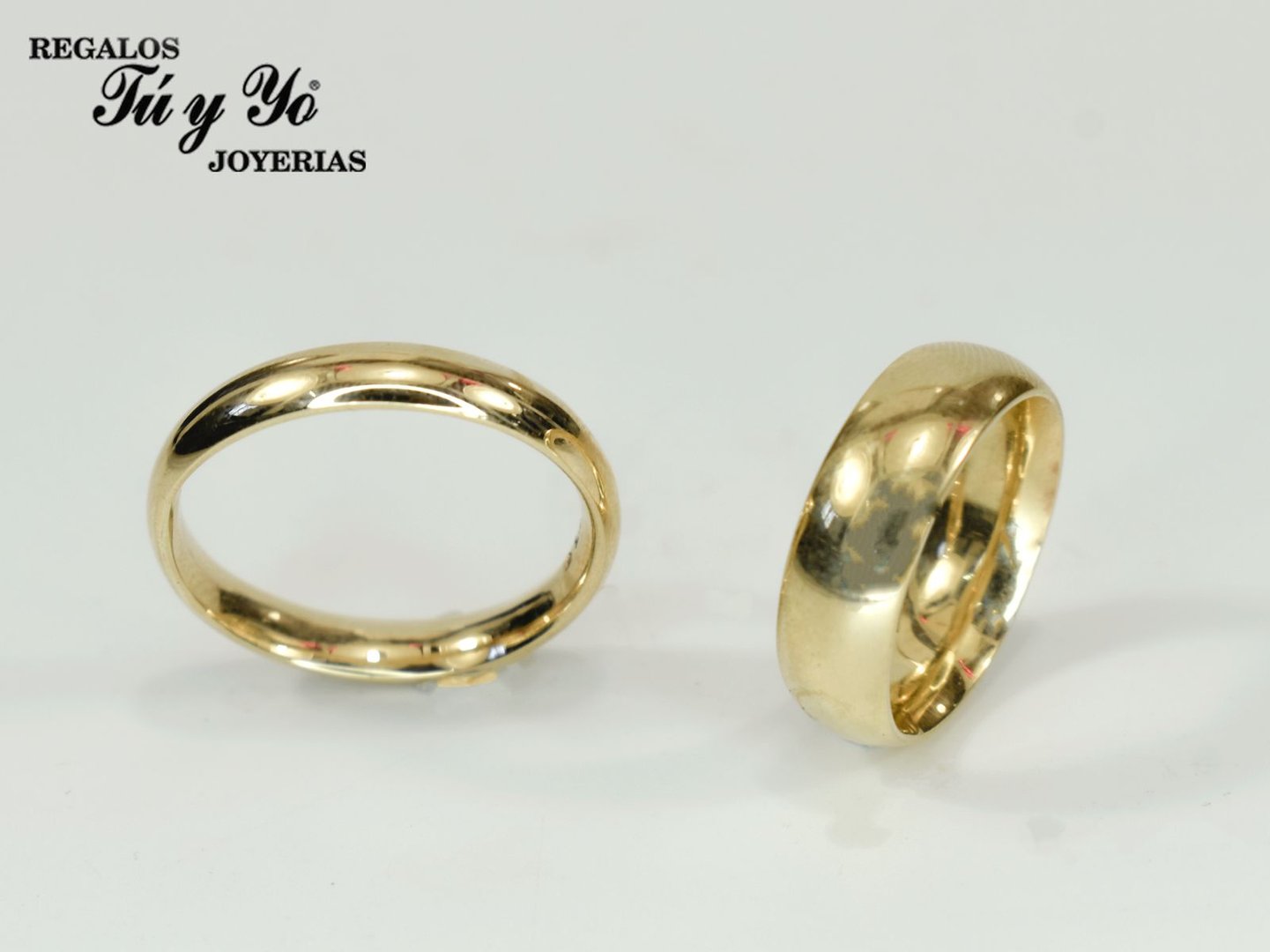 Two gold rings displayed on a white surface with the text 'Regalos Tú y Yo joyerías' in the top left corner.